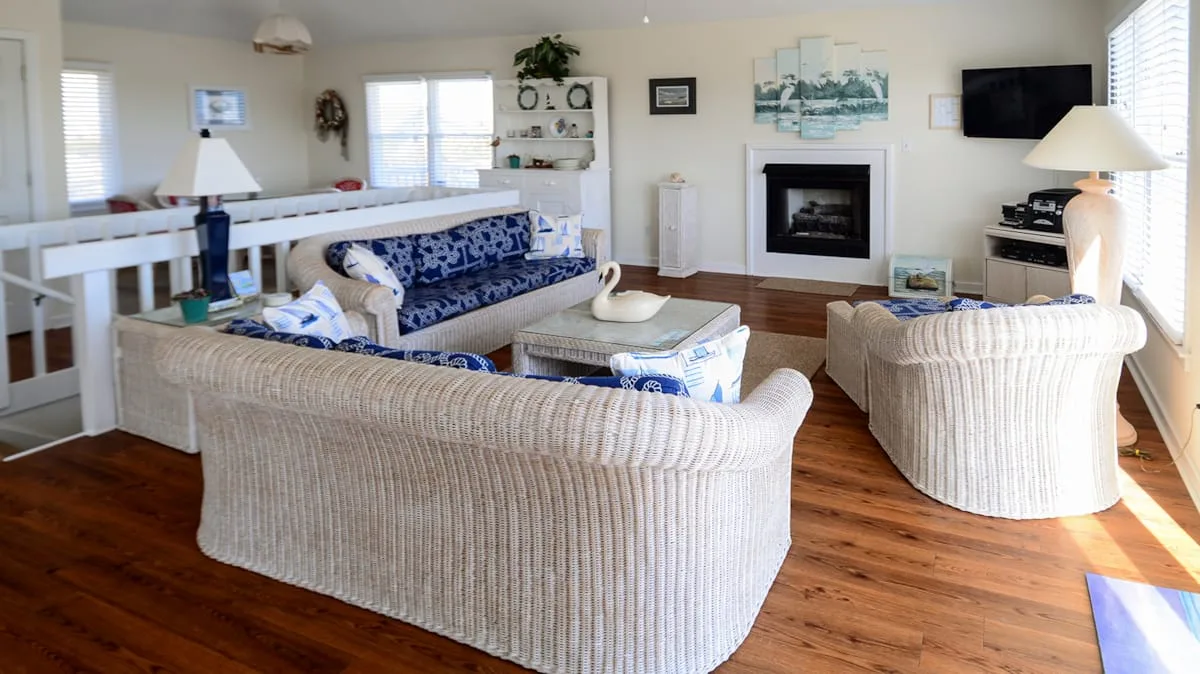 A living room with woven seating arranged around a coffee table and fireplace.