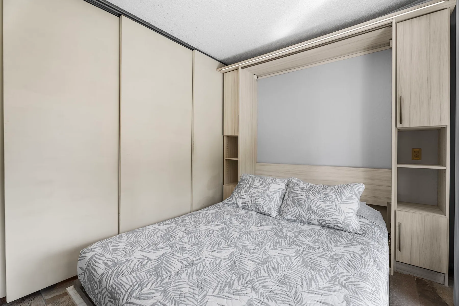 Un dormitorio con una cama vestida con ropa de cama gris estampada.