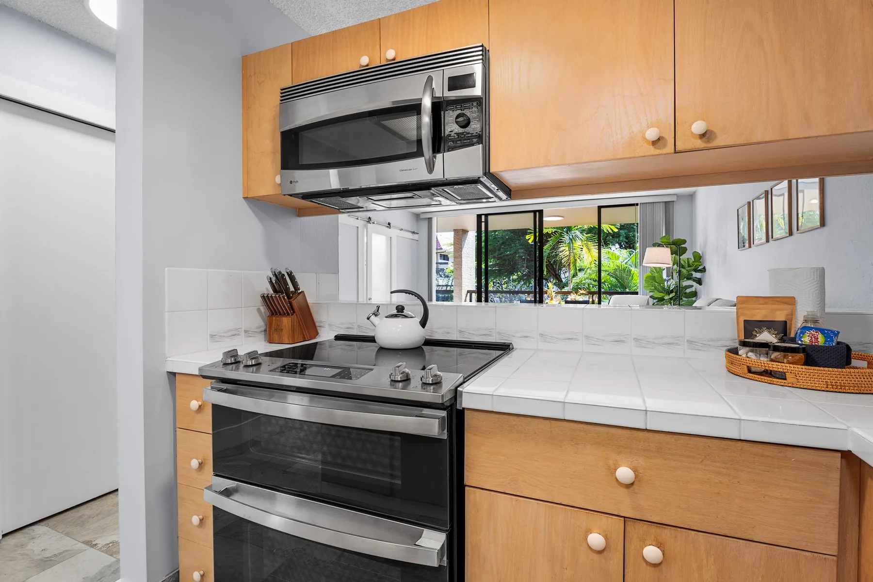 Una cocina luminosa con estufa, microondas y gabinetes de madera.