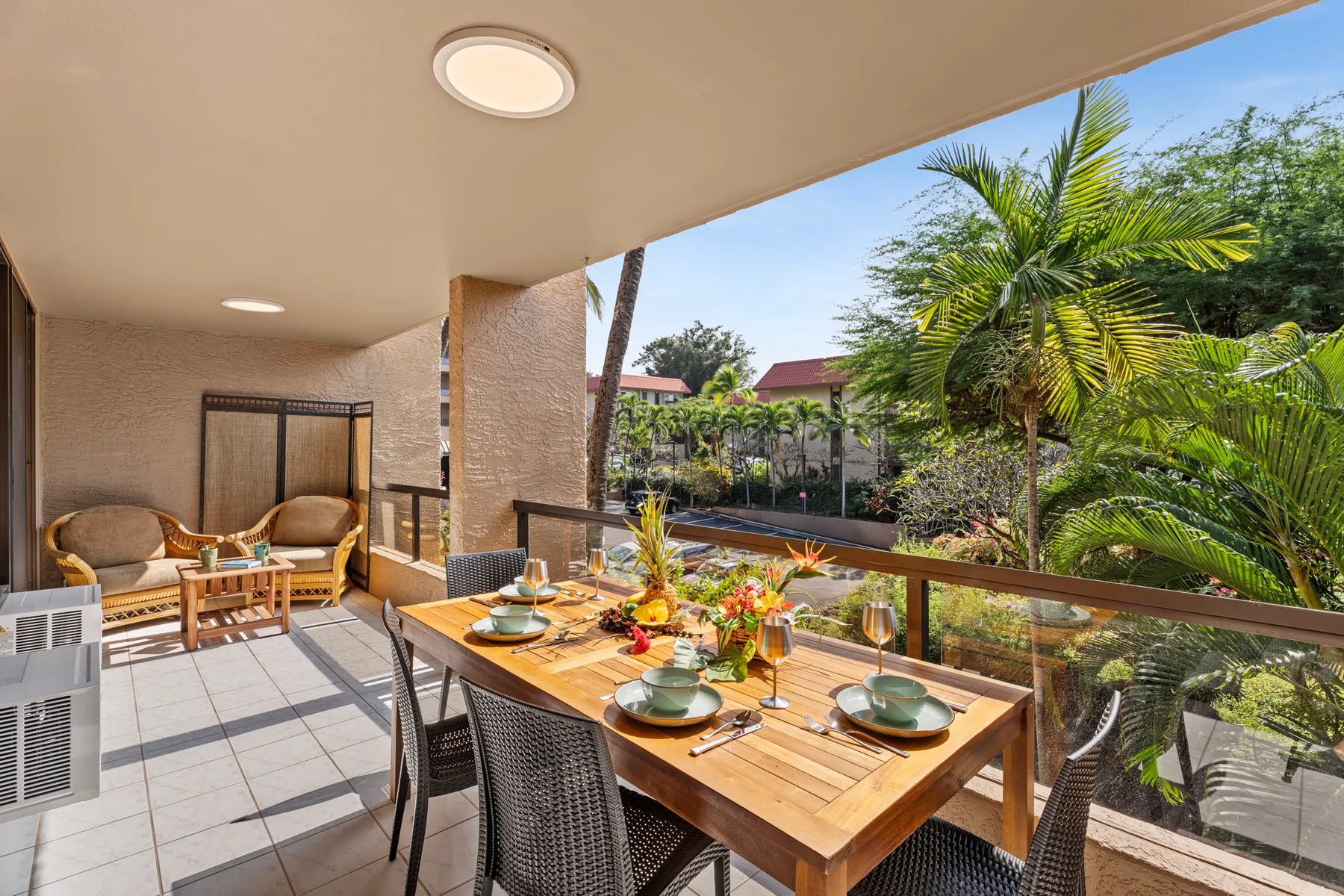 Un comedor exterior cubierto con una mesa de madera frente a un jardín frondoso.