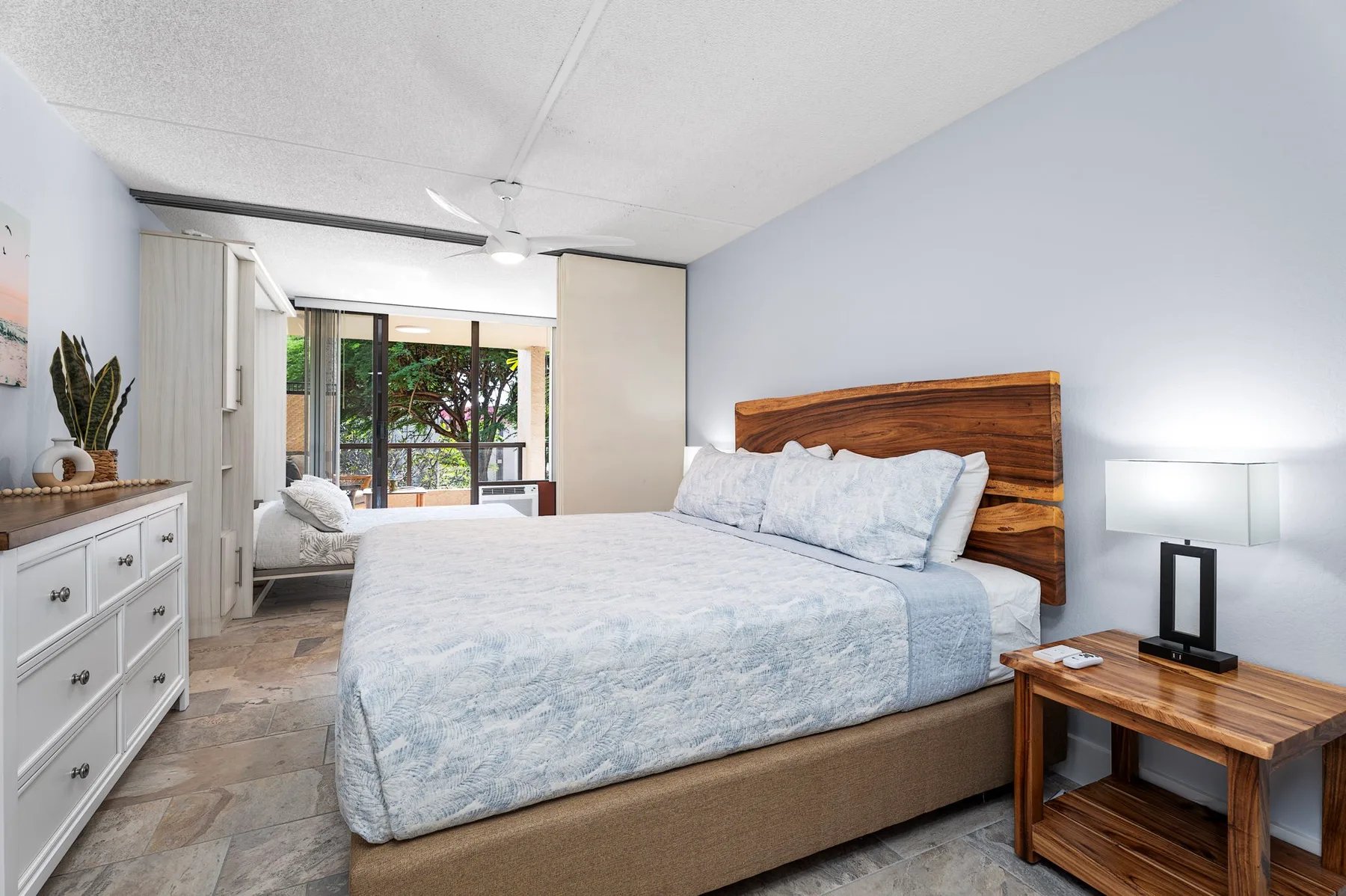 Un dormitorio con una cama, cabecero de madera y una ventana con vista a la vegetación.
