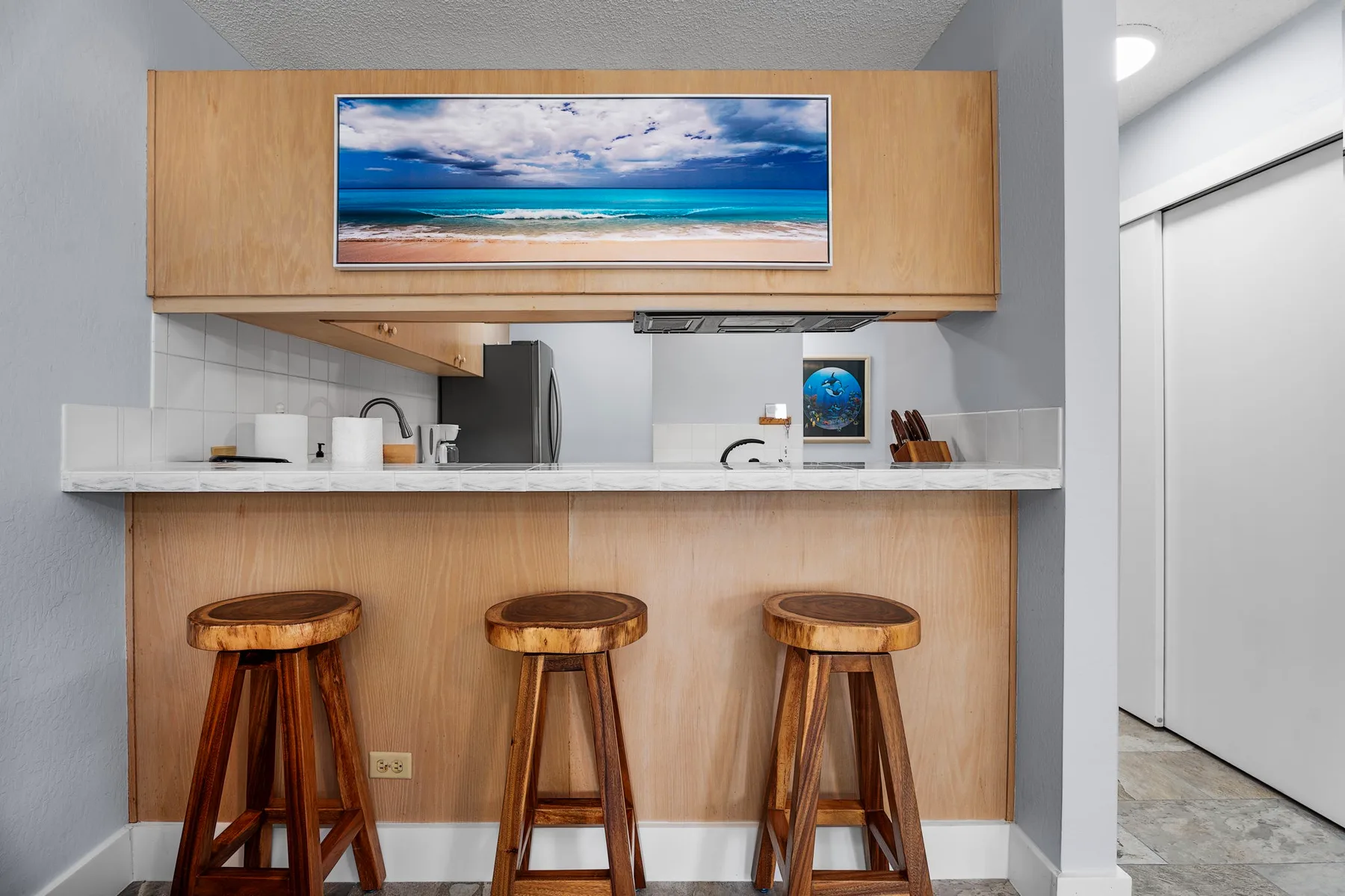 Una cocina compacta con una barra elevada y taburetes de madera.