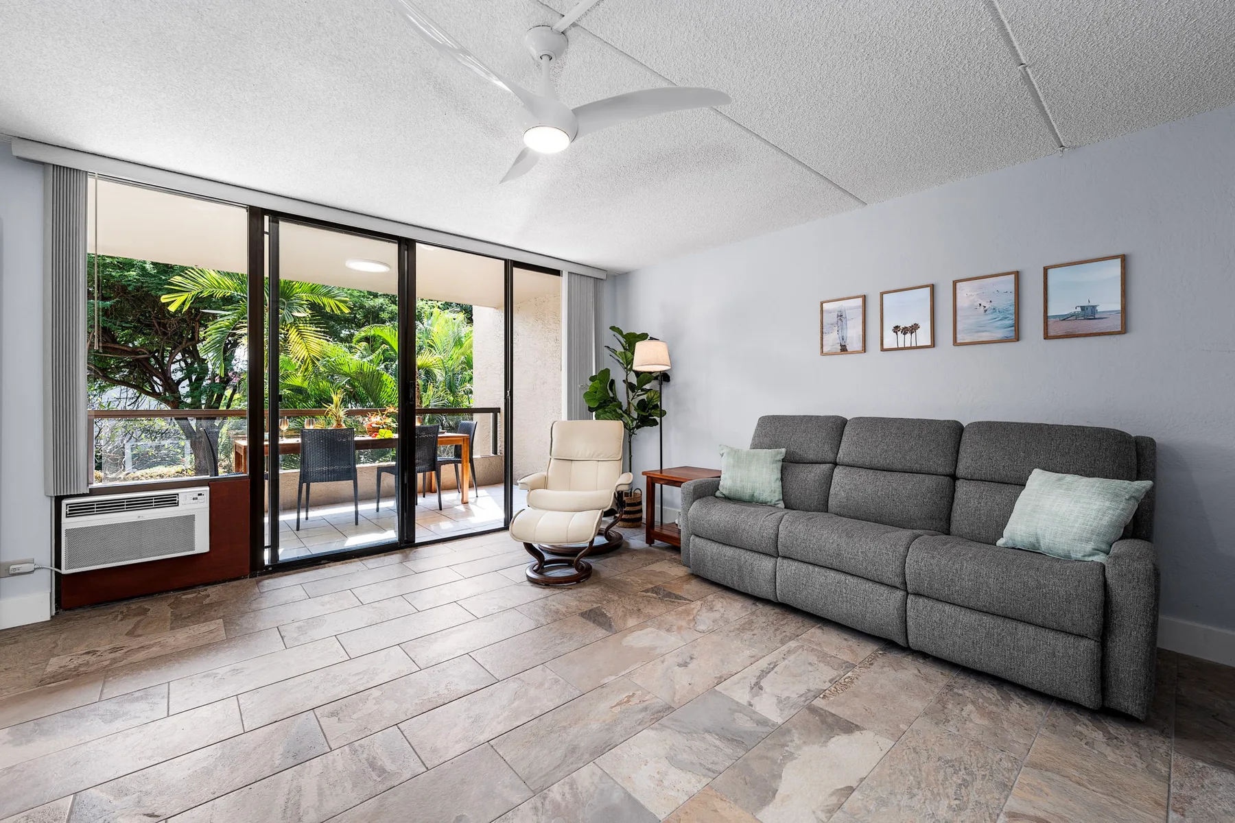 Una sala de estar con un sofá gris y puertas corredizas de vidrio que dan a un patio.