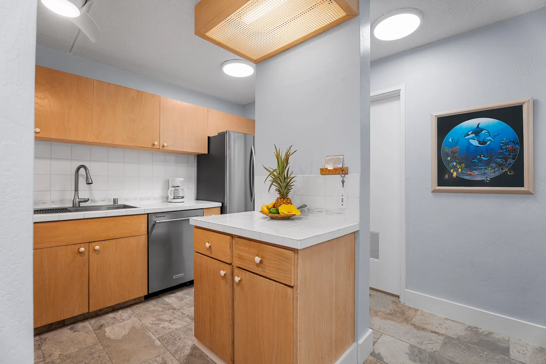 Una cocina con gabinetes de madera y una isla central con fruta.