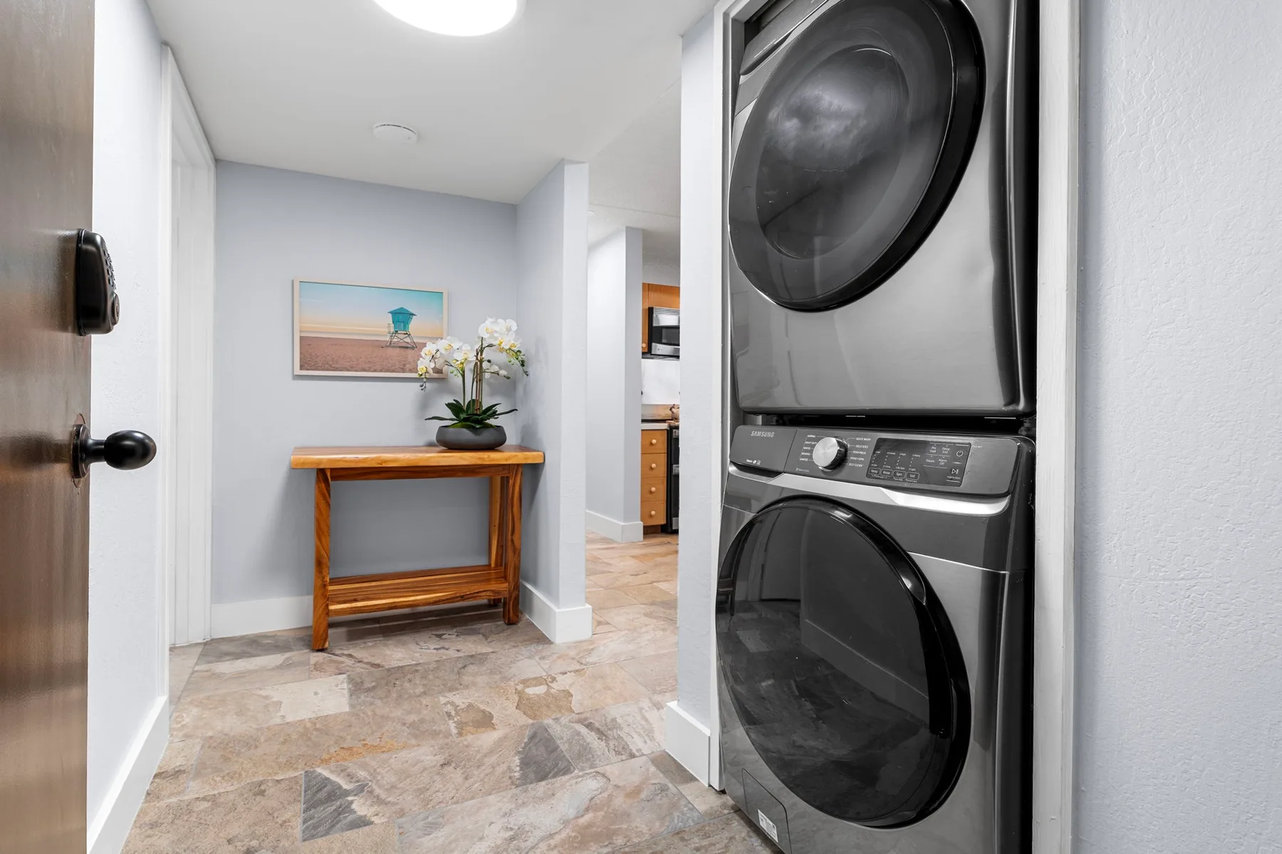 Una zona de lavandería con electrodomésticos apilados junto a una pequeña mesa de madera.