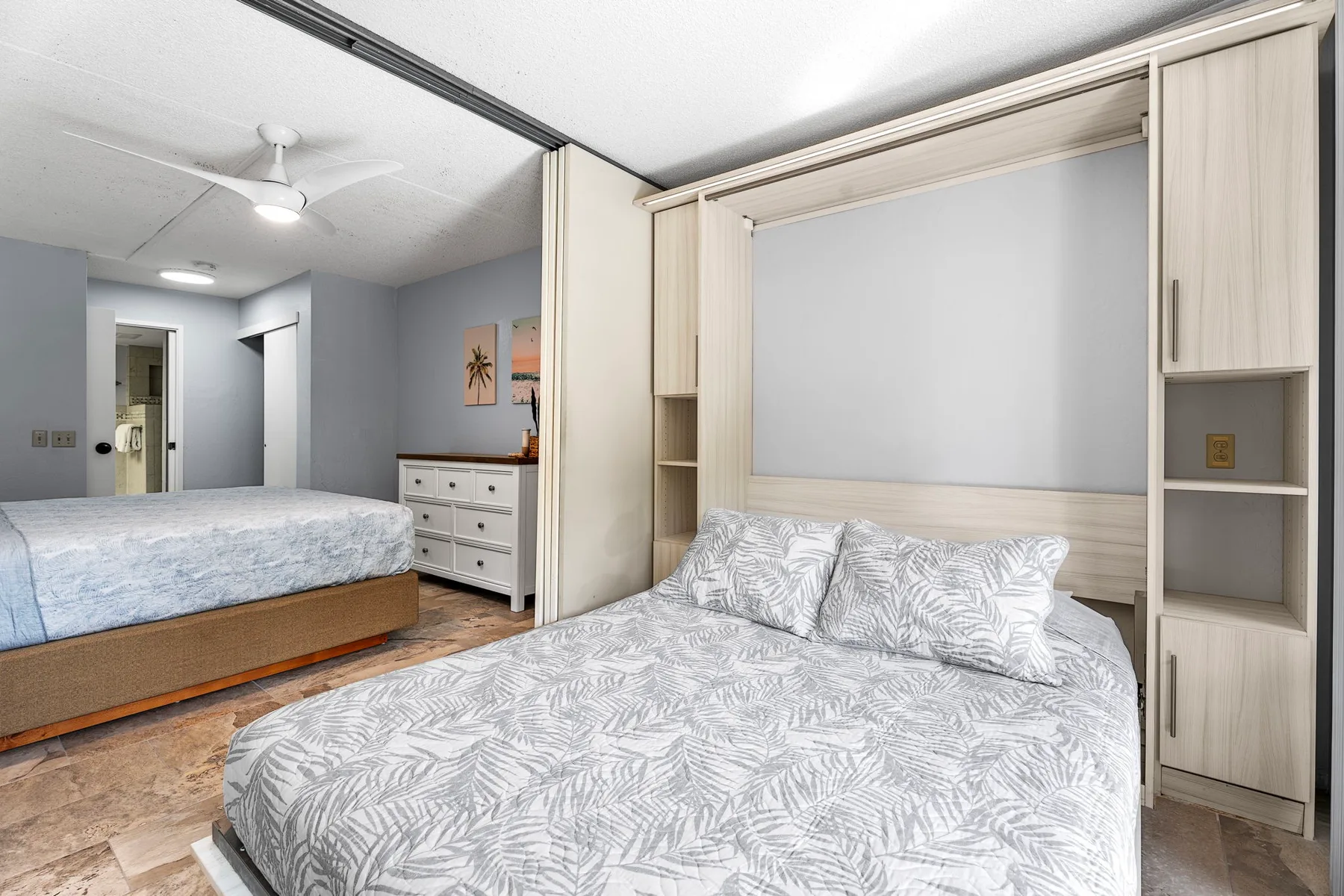 Un dormitorio con una cama grande, ropa de cama estampada y almacenamiento integrado.