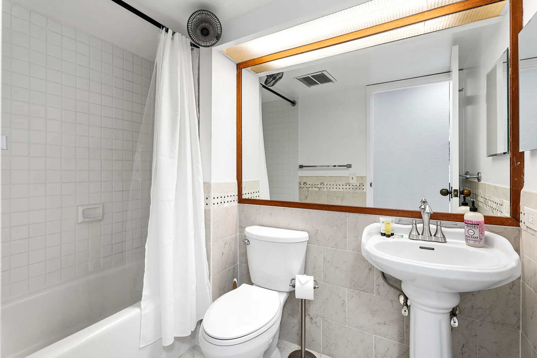 Un baño alicatado con inodoro, lavabo y un espejo grande.