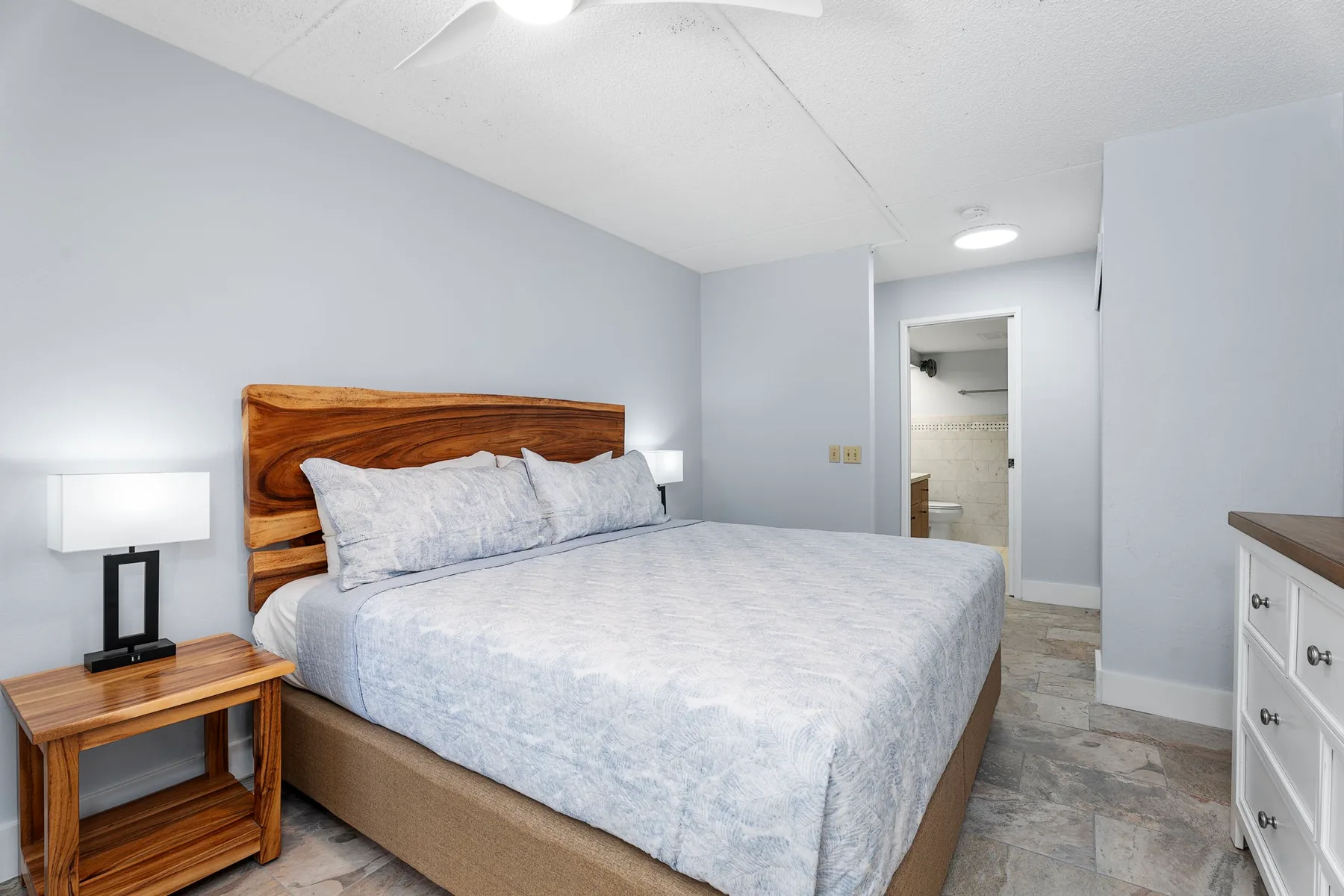 Un dormitorio con una cama, cabecero de madera y mesas de noche.