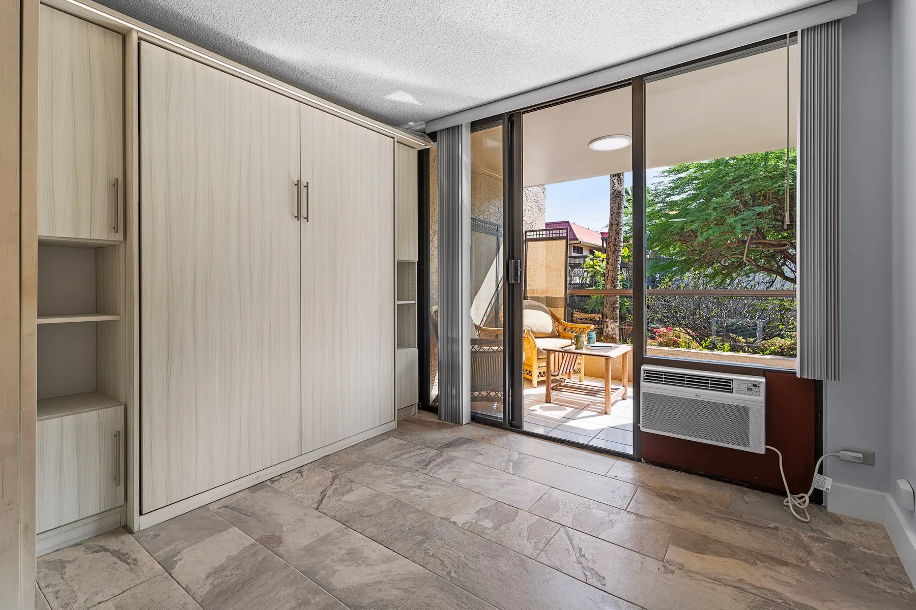 Una habitación luminosa con armarios empotrados y puertas corredizas de vidrio que dan a un patio.