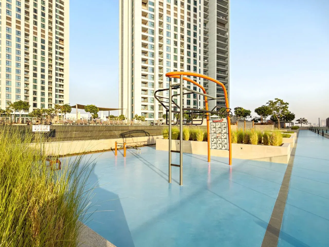 An outdoor play area with climbing equipment stands beside tall residential buildings.