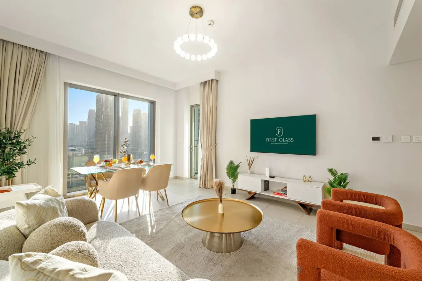 A bright living room with seating, a coffee table, and large windows overlooking city buildings.