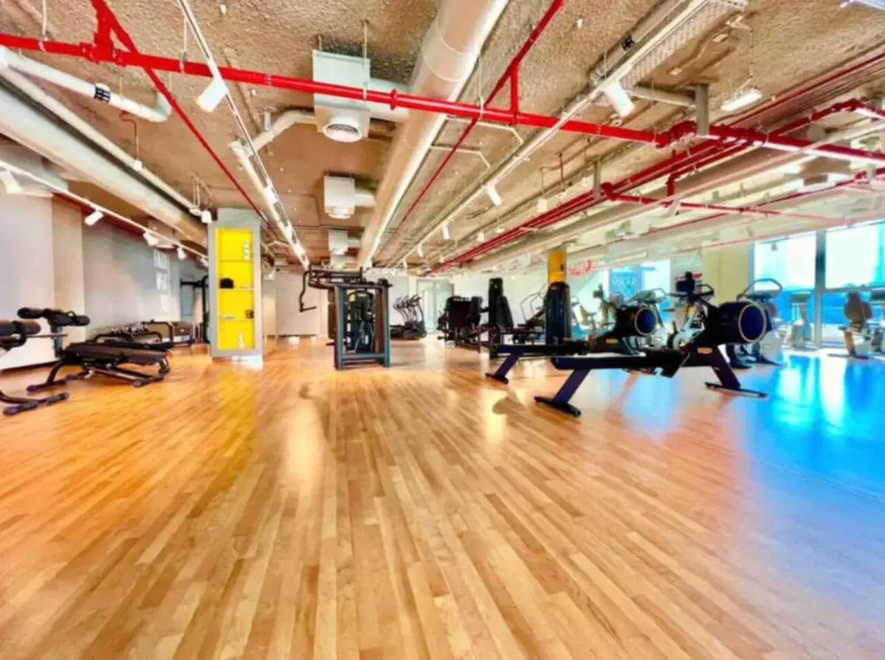 A gym with exercise equipment arranged across a wood-floored room.