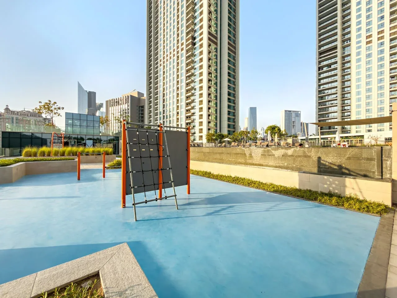 An outdoor recreation area with a blue court surface and tall buildings nearby.