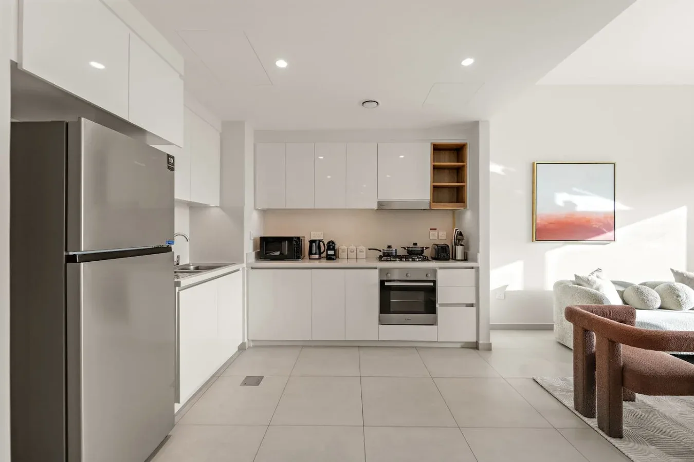 A bright modern kitchen opens into a living area with seating.