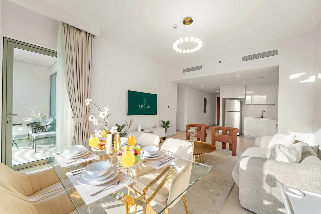 A bright dining and living area features a glass dining table and seating.