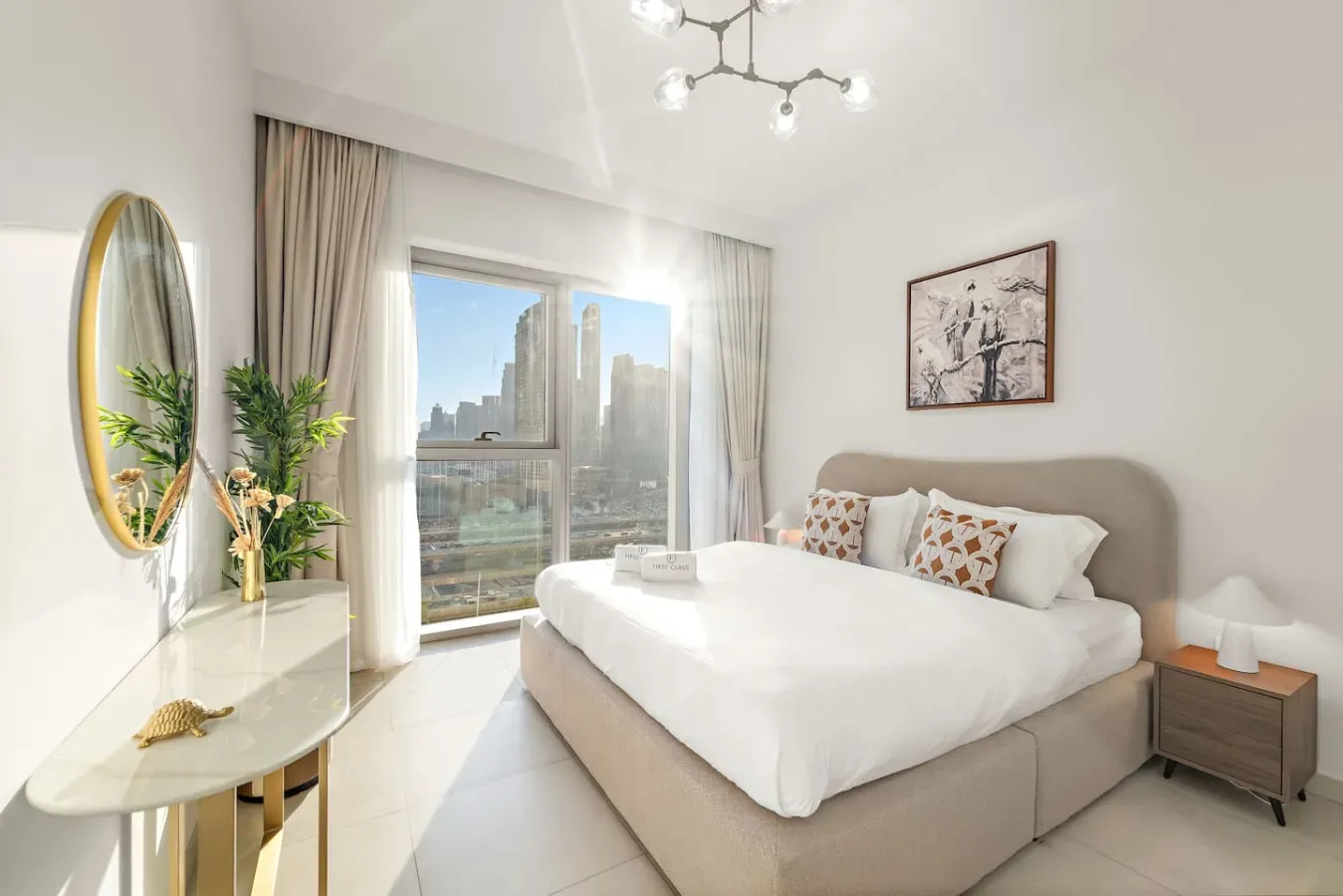 A bright bedroom with a large bed beside a window overlooking city buildings.