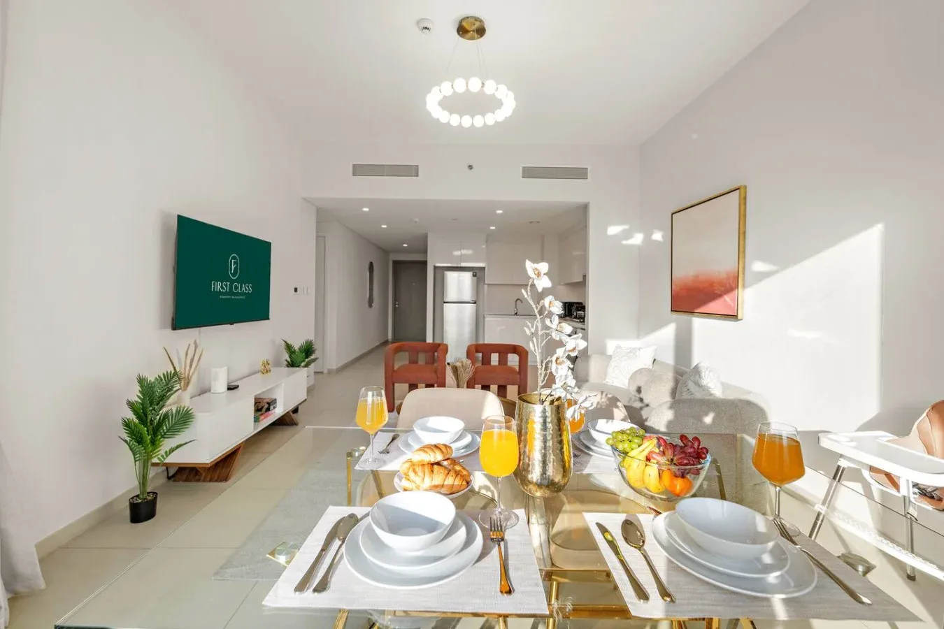A bright dining area with a set table and a living space beyond.