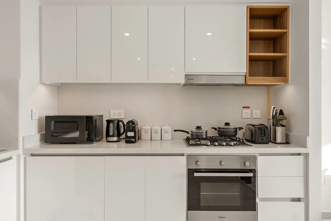 A modern kitchen with white cabinets, countertop appliances, and a built-in oven.
