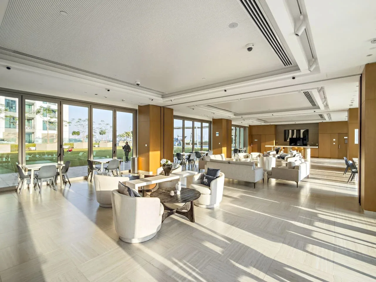 A bright lounge with seating and large windows overlooking landscaped grounds.