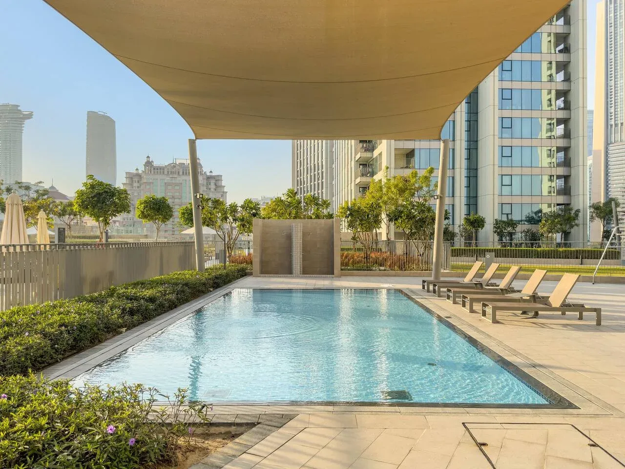A swimming pool sits beneath a canopy, with lounge chairs along the deck.