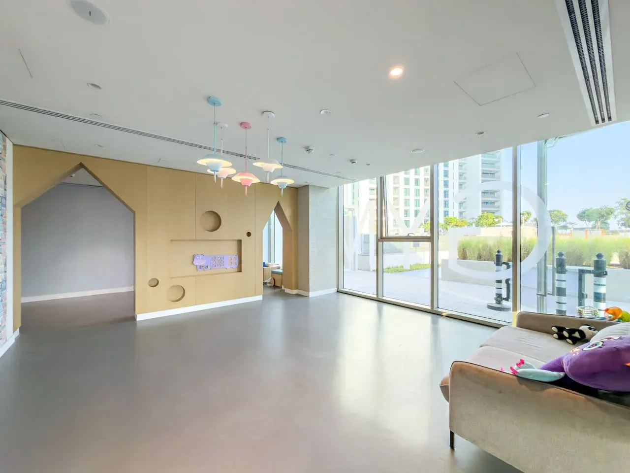 A bright indoor lounge with colorful hanging lights and large windows.