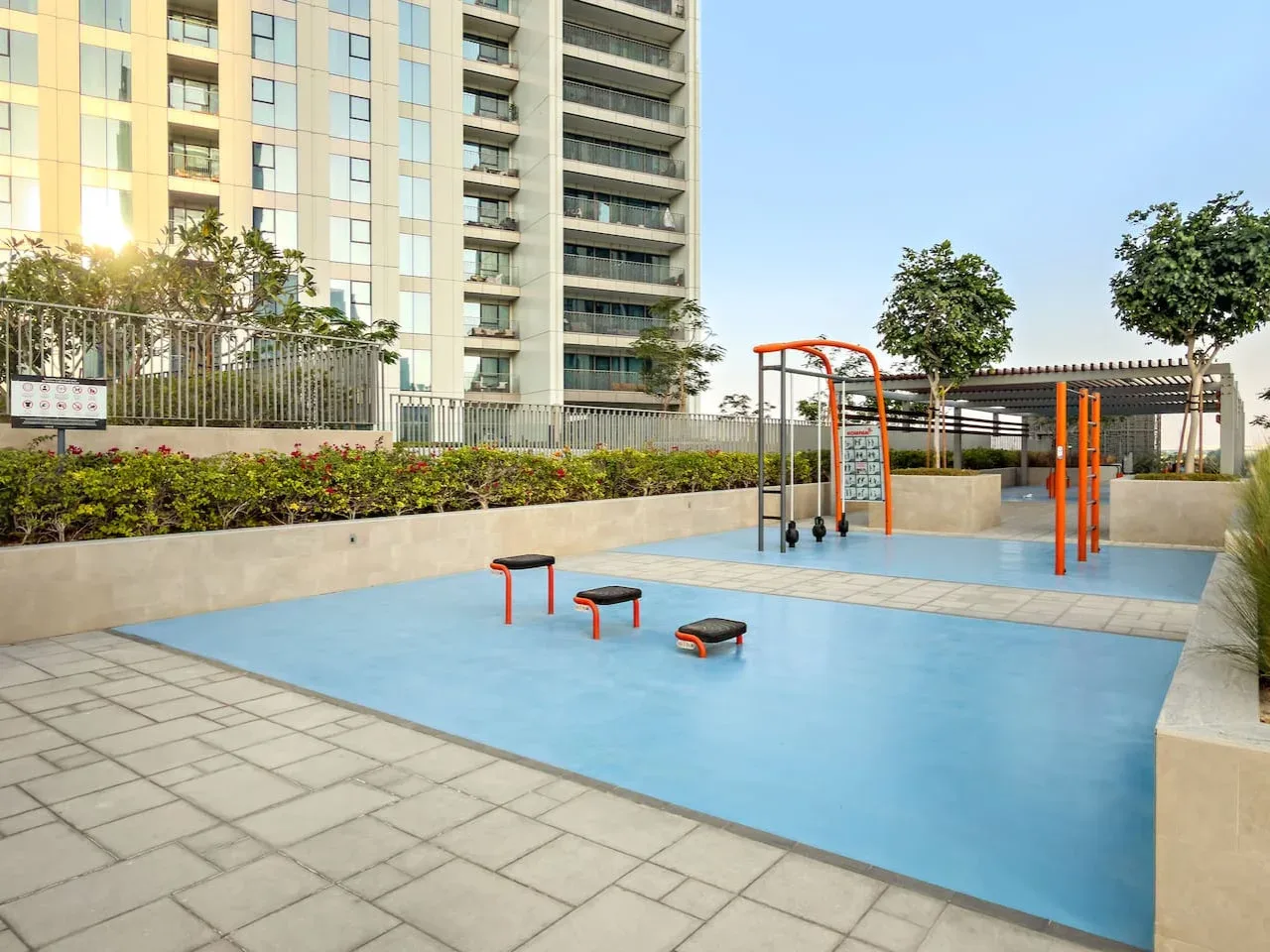 An outdoor fitness area with exercise equipment beside a high-rise building.