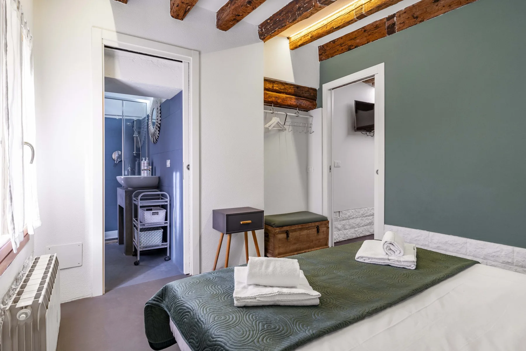 Un dormitorio con la cama bien arreglada y una puerta abierta al baño.