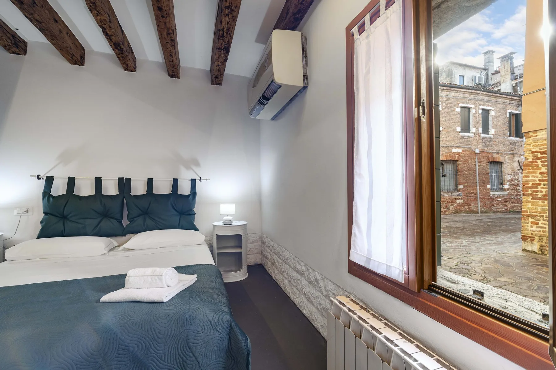 Un dormitorio con una cama junto a una ventana alta.