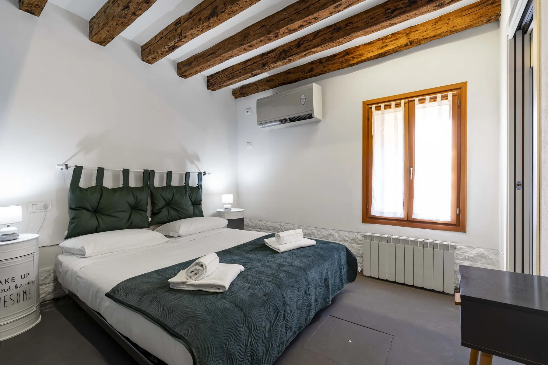 Un dormitorio con una cama doble, toallas dobladas y una ventana.