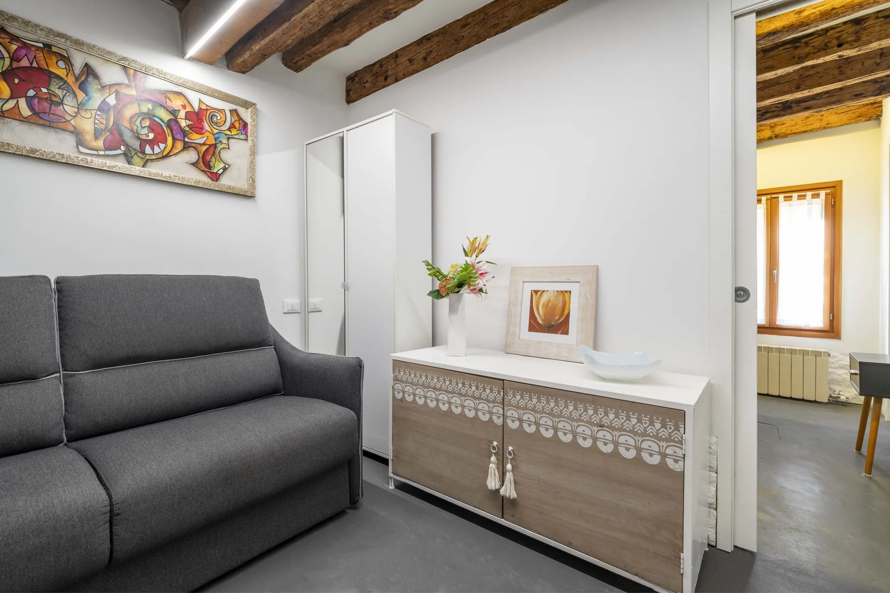 Una sala de estar con asientos oscuros junto a un aparador de madera decorado.