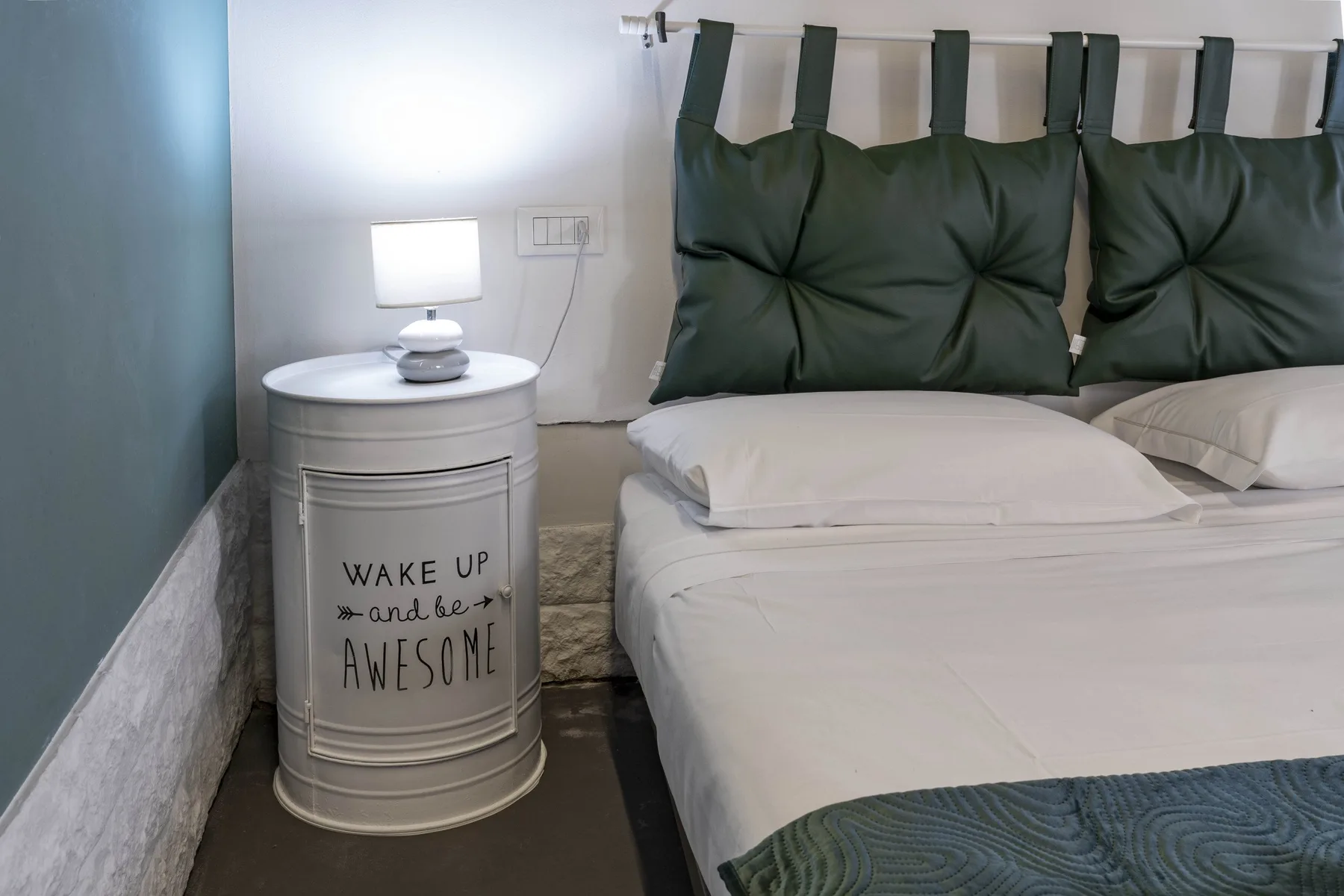 Un dormitorio con ropa de cama blanca y cabeceros acolchados oscuros.