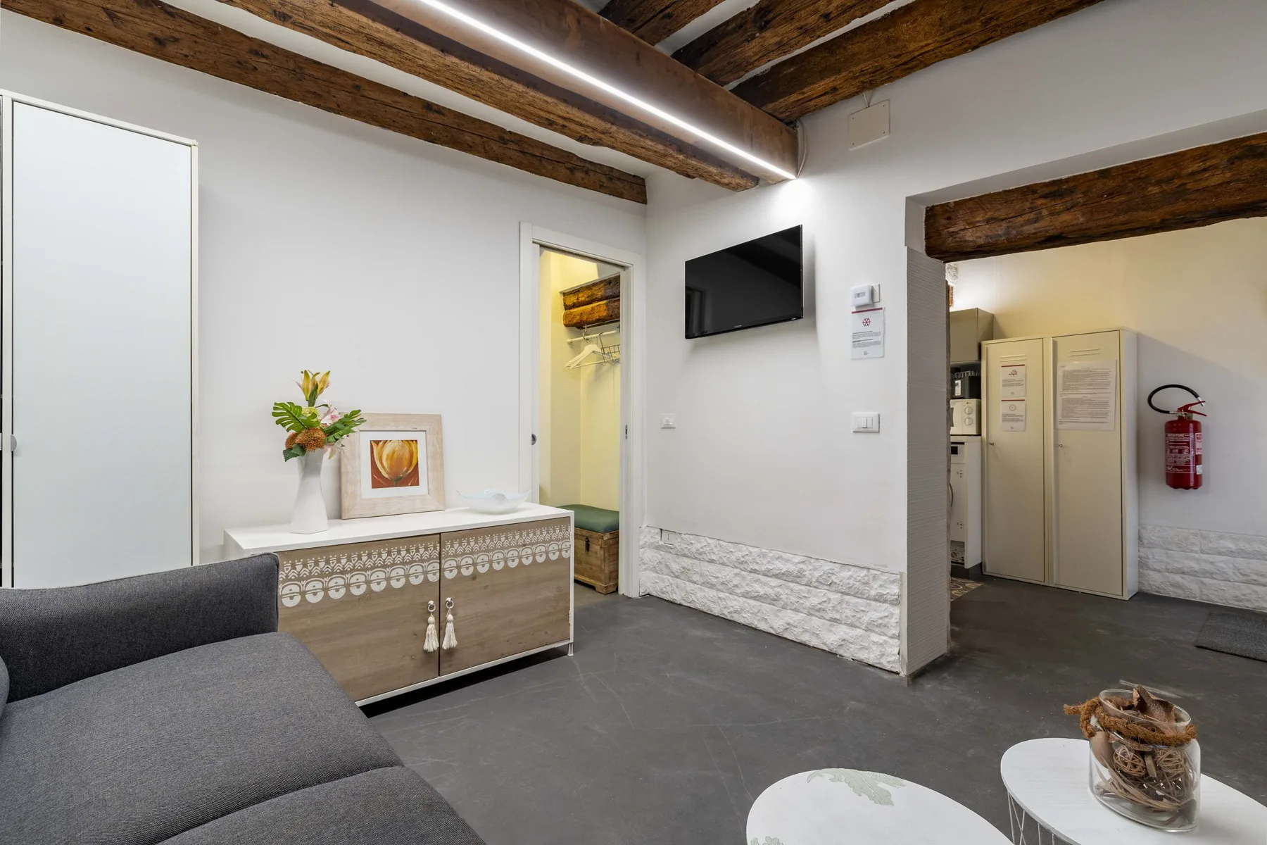Una sala luminosa con vigas de madera expuestas, un televisor y asientos.