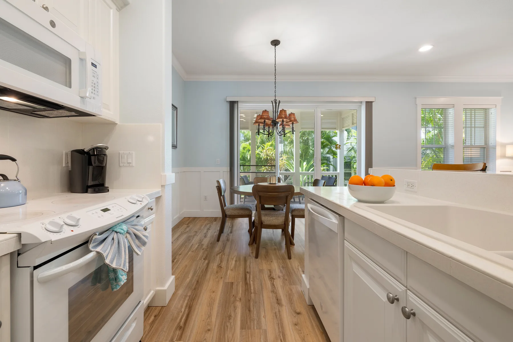 Una cocina luminosa se abre a un comedor, con una barra y una mesa.