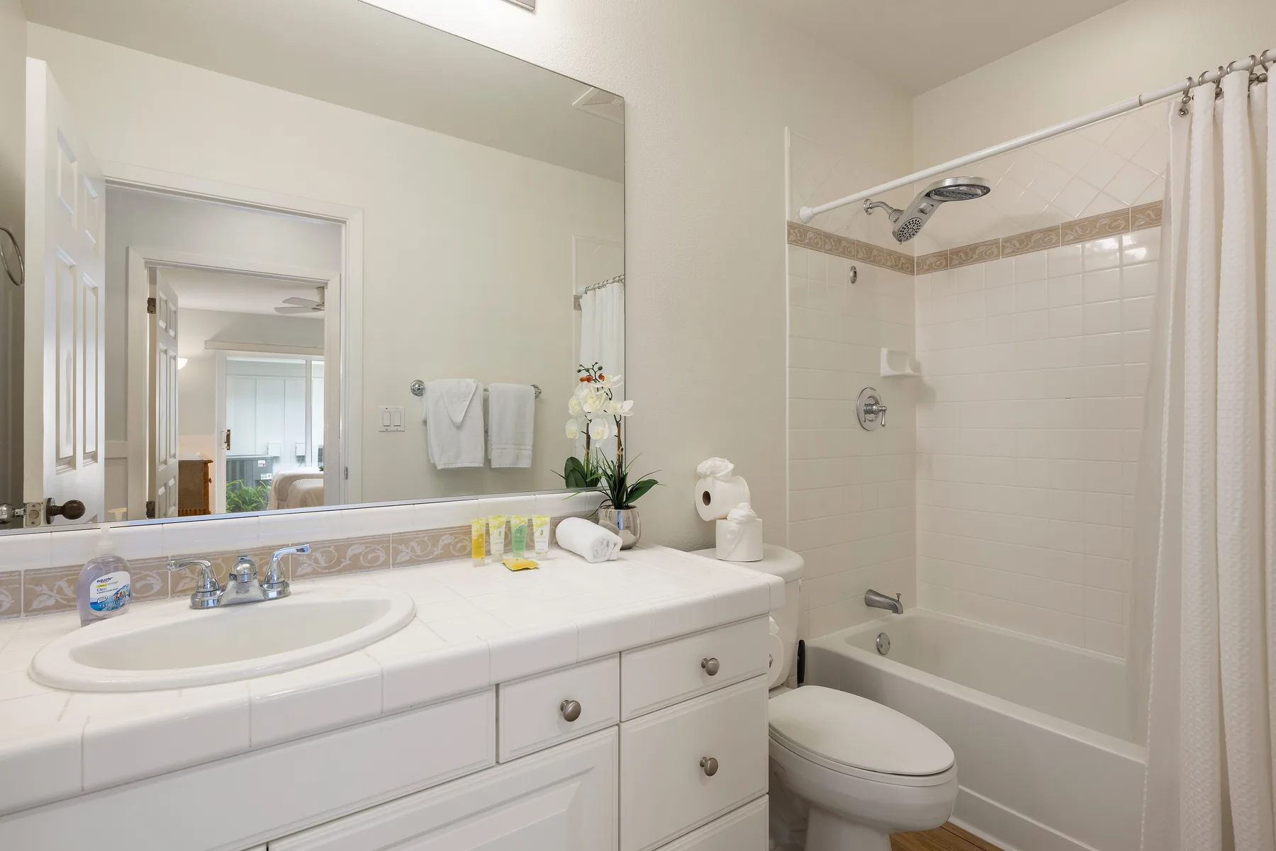 Un baño luminoso con lavabo y bañera con ducha.