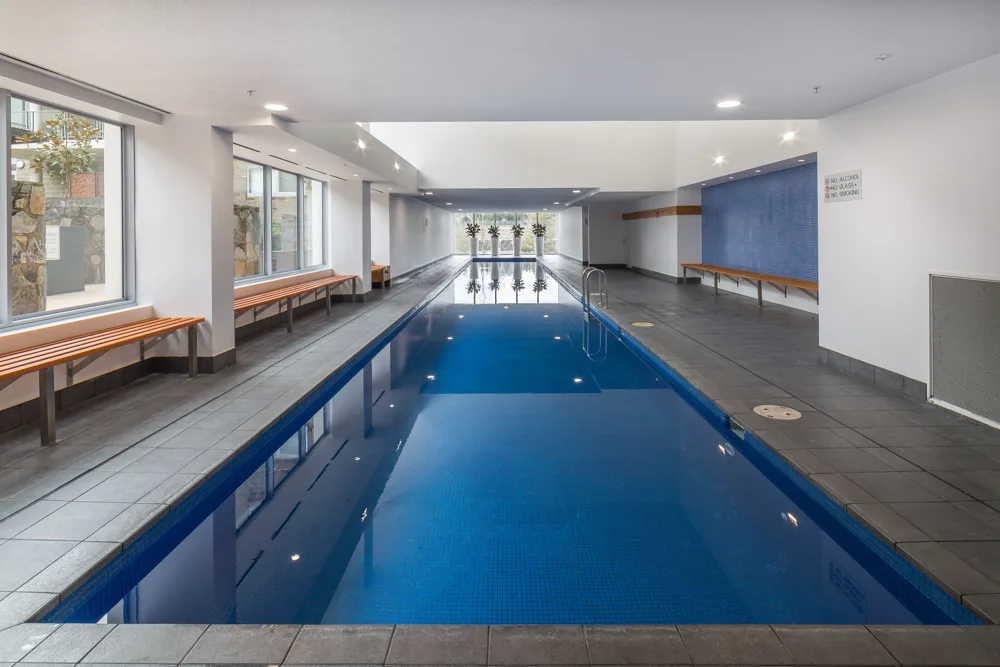 Una piscina cubierta en una sala amplia con bancos junto a las paredes.