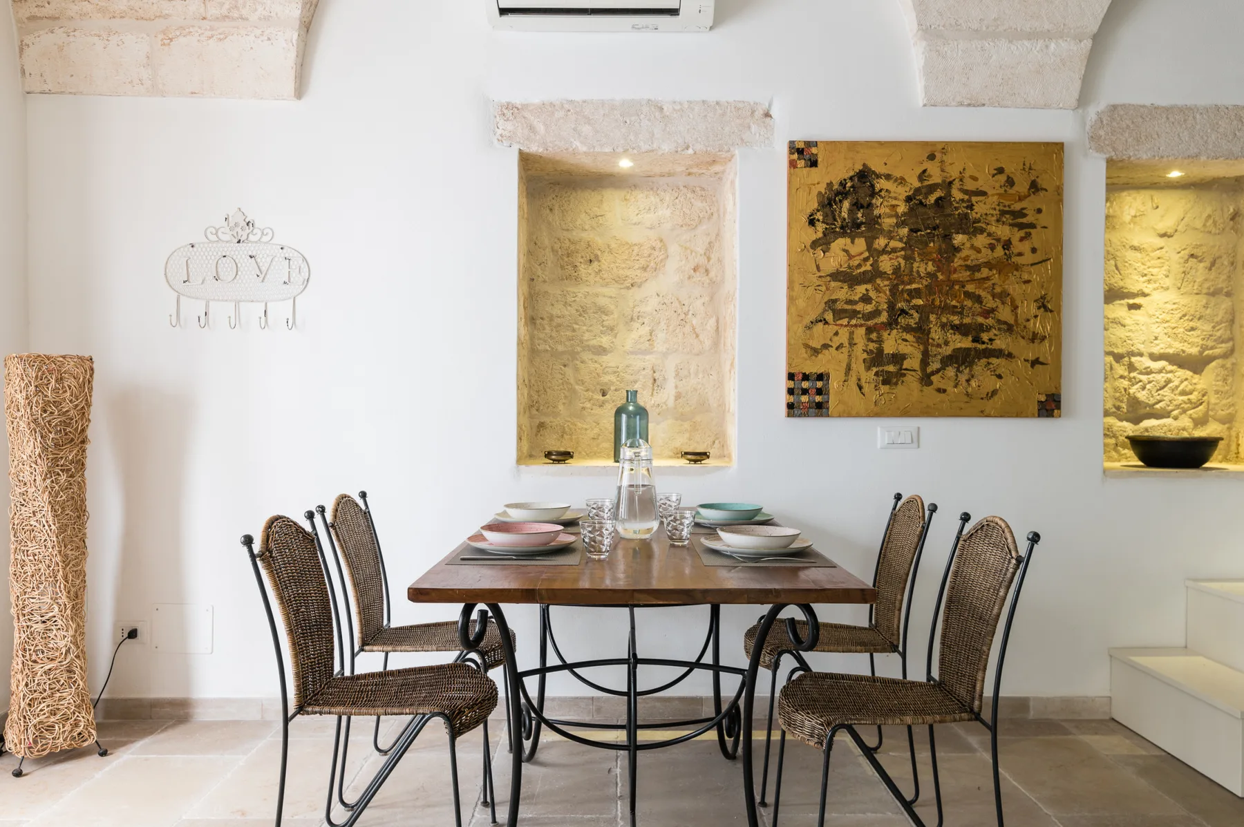A dining area with a wooden table set beneath a large wall artwork.