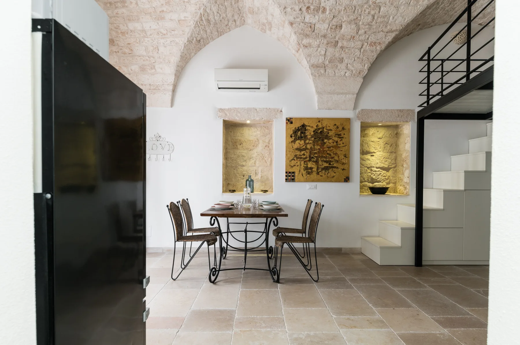 Un comedor con una mesa y sillas bajo un arco de ladrillo.