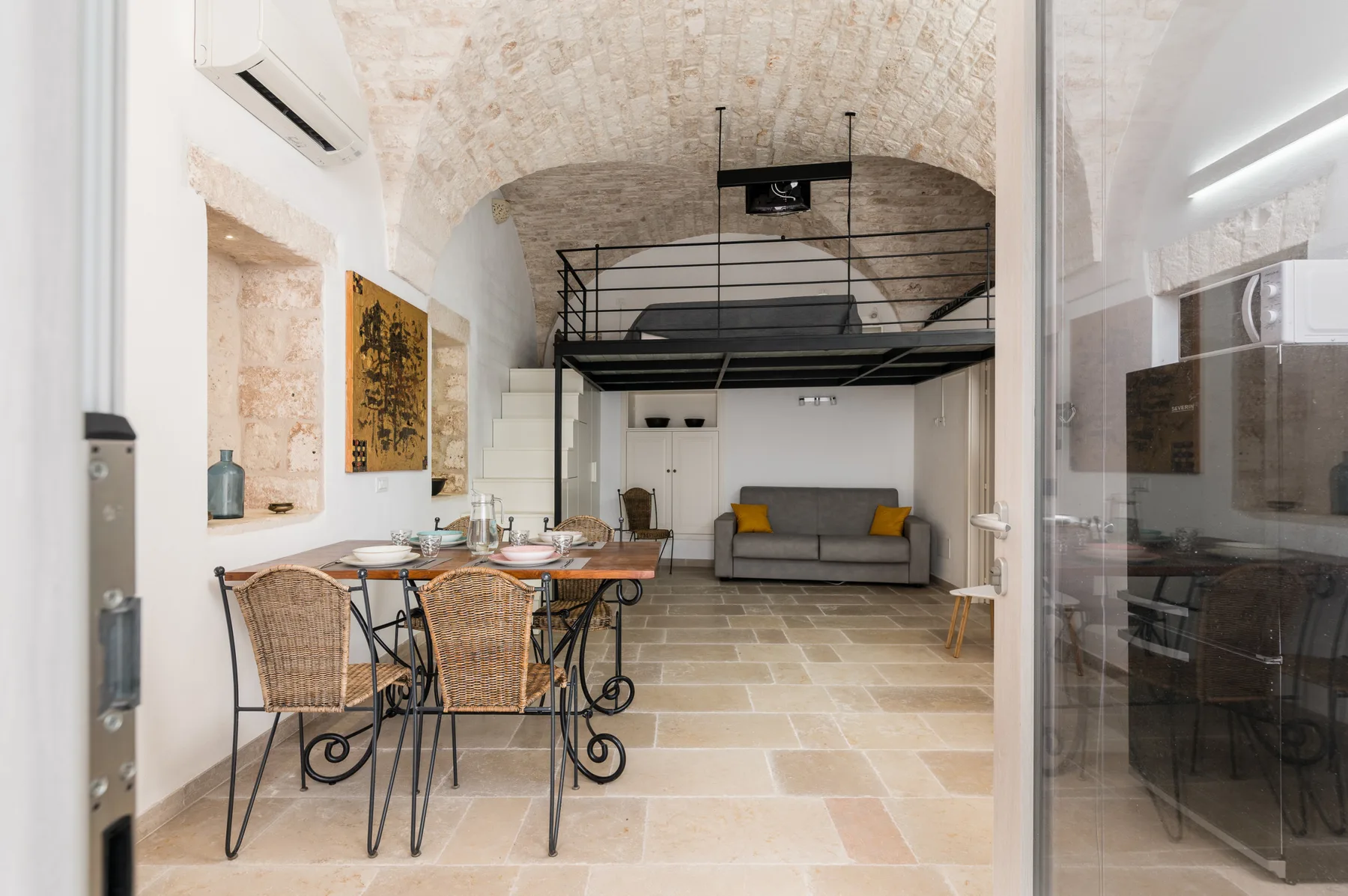 A bright living and dining area with a table, seating, and a raised sleeping platform.