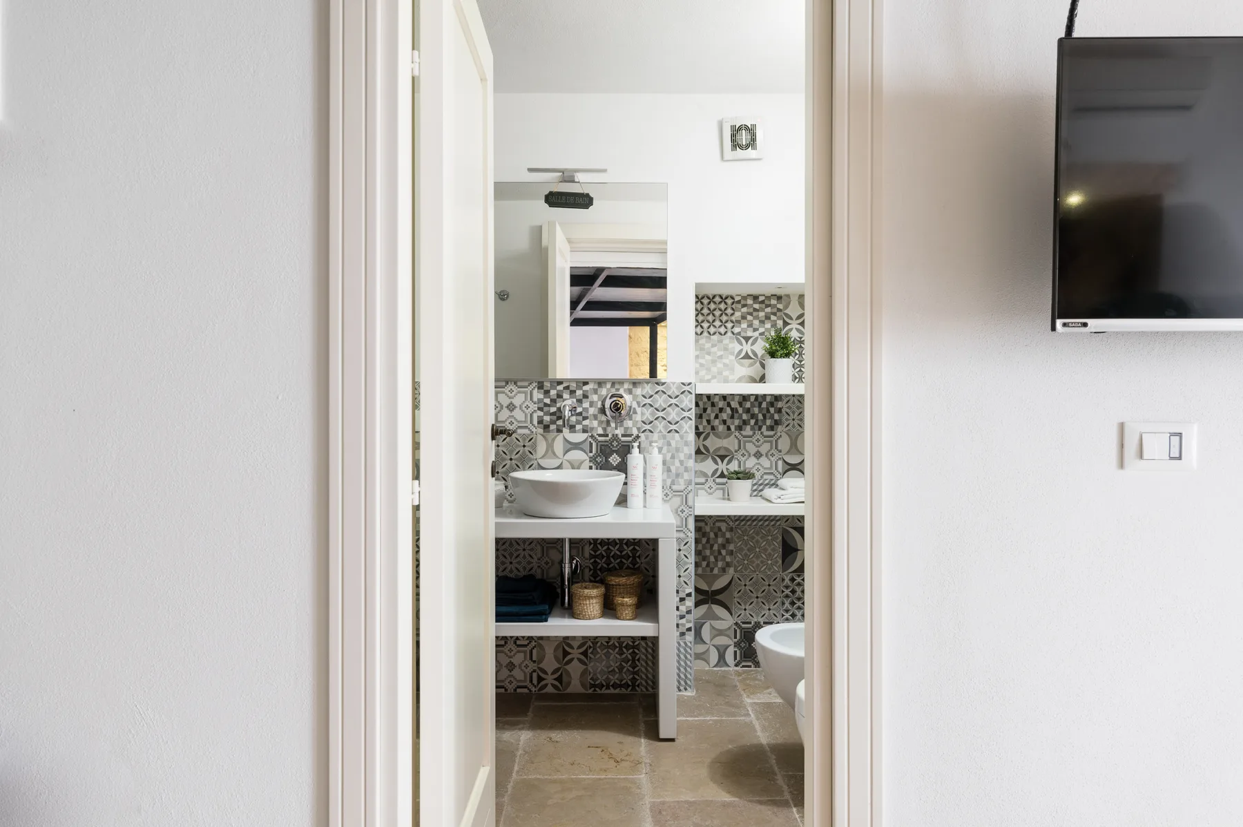 Un baño con azulejos estampados, un lavabo y un espejo.