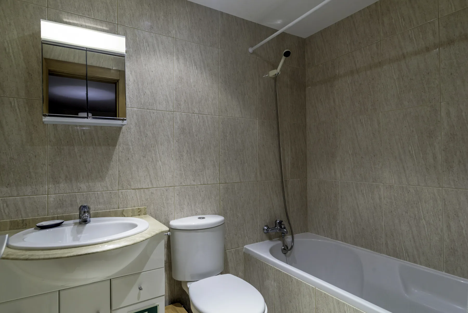 Un baño alicatado con lavabo, inodoro y bañera.