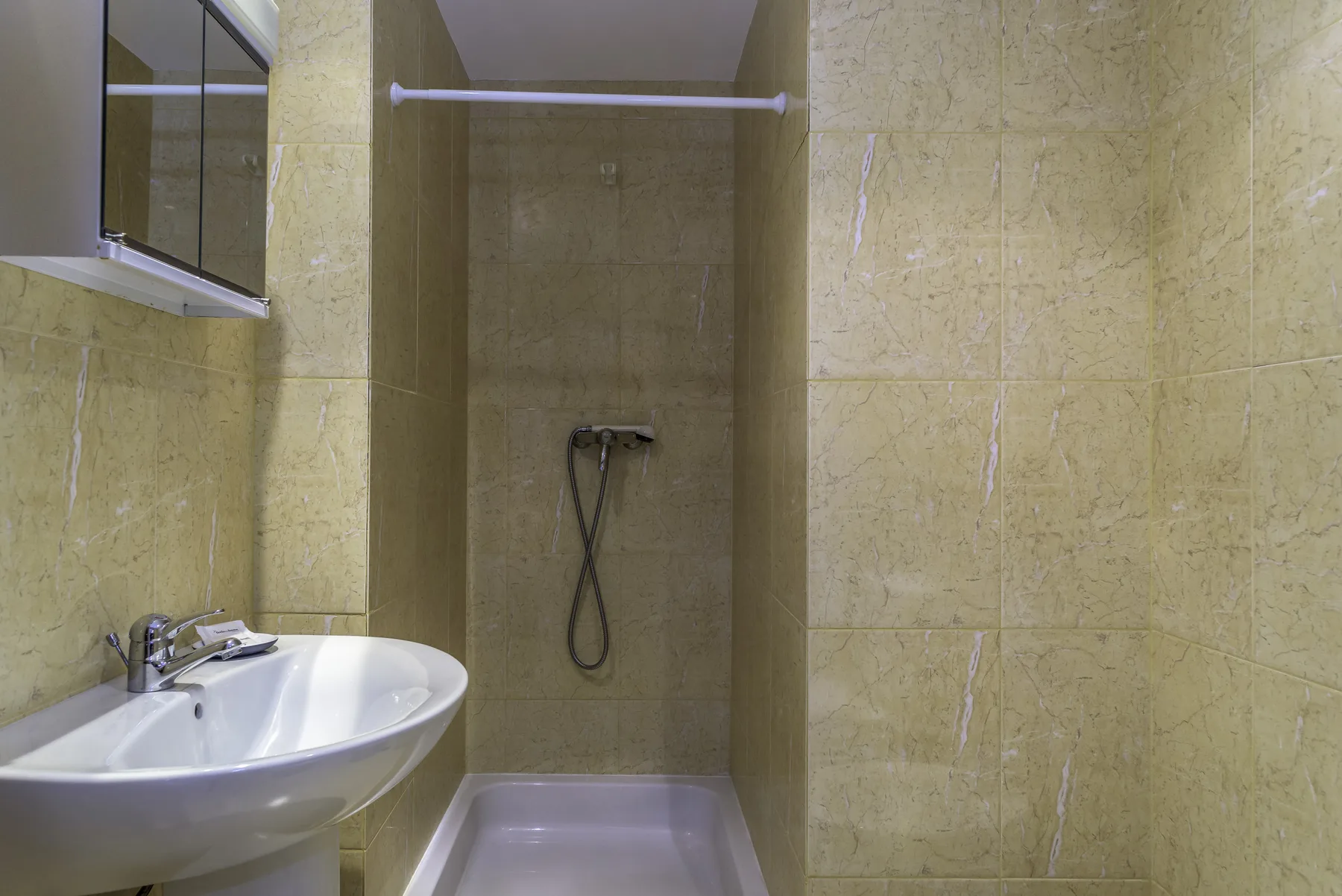 Un baño con azulejos, lavabo y ducha.