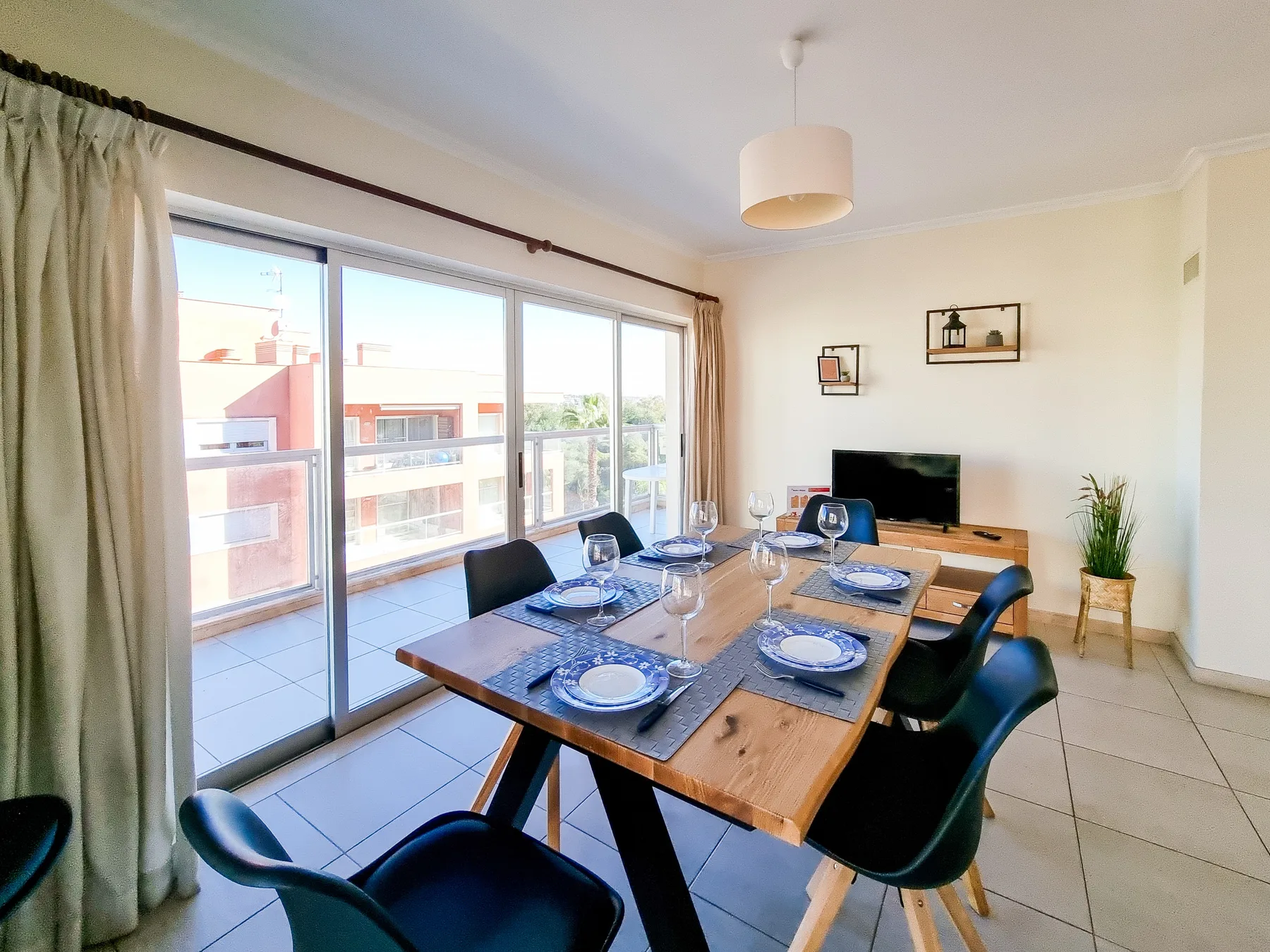 Comedor con mesa de madera y grandes puertas de vidrio que dan a un balcón.