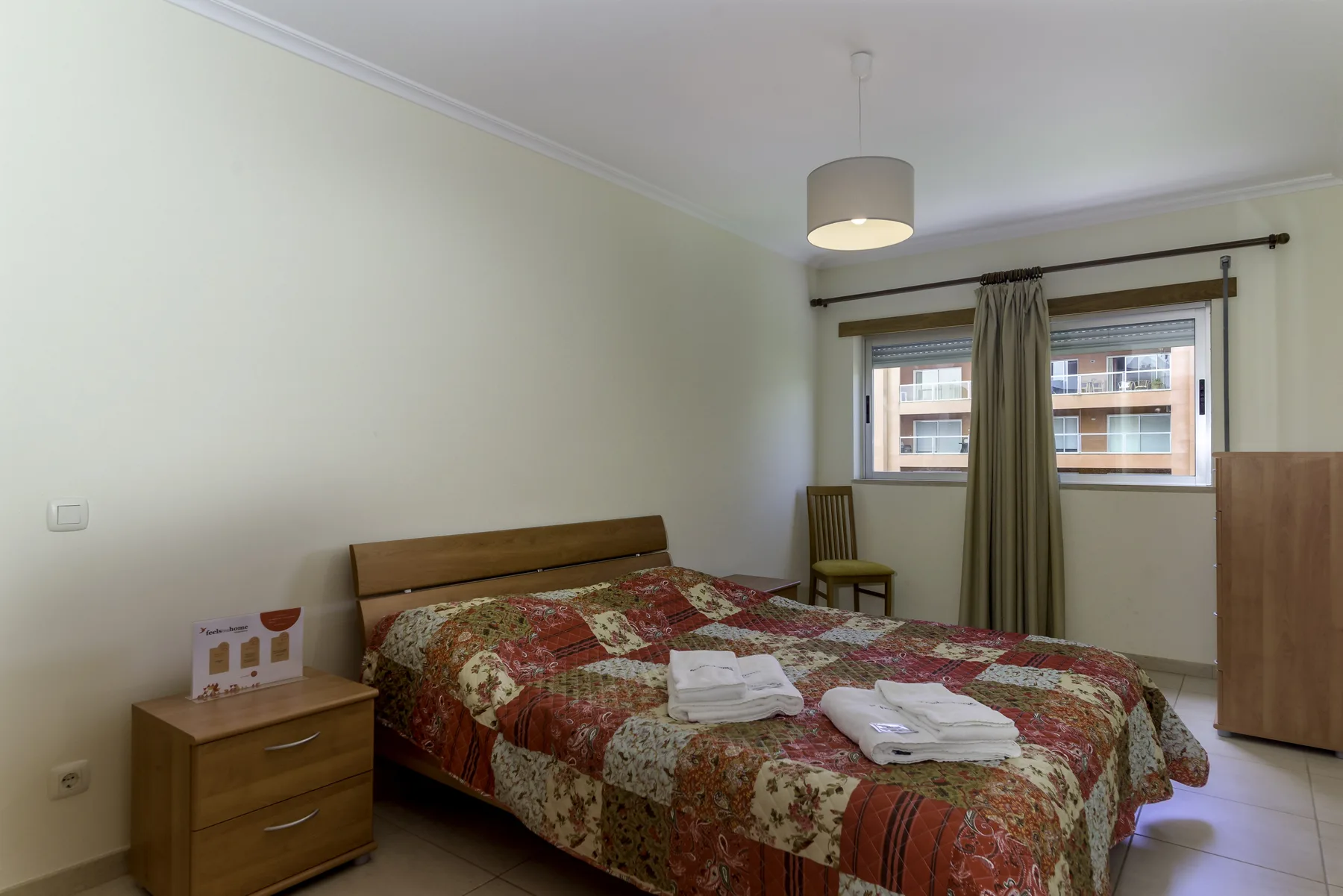 Un dormitorio con una cama cubierta por una colcha estampada y una ventana.