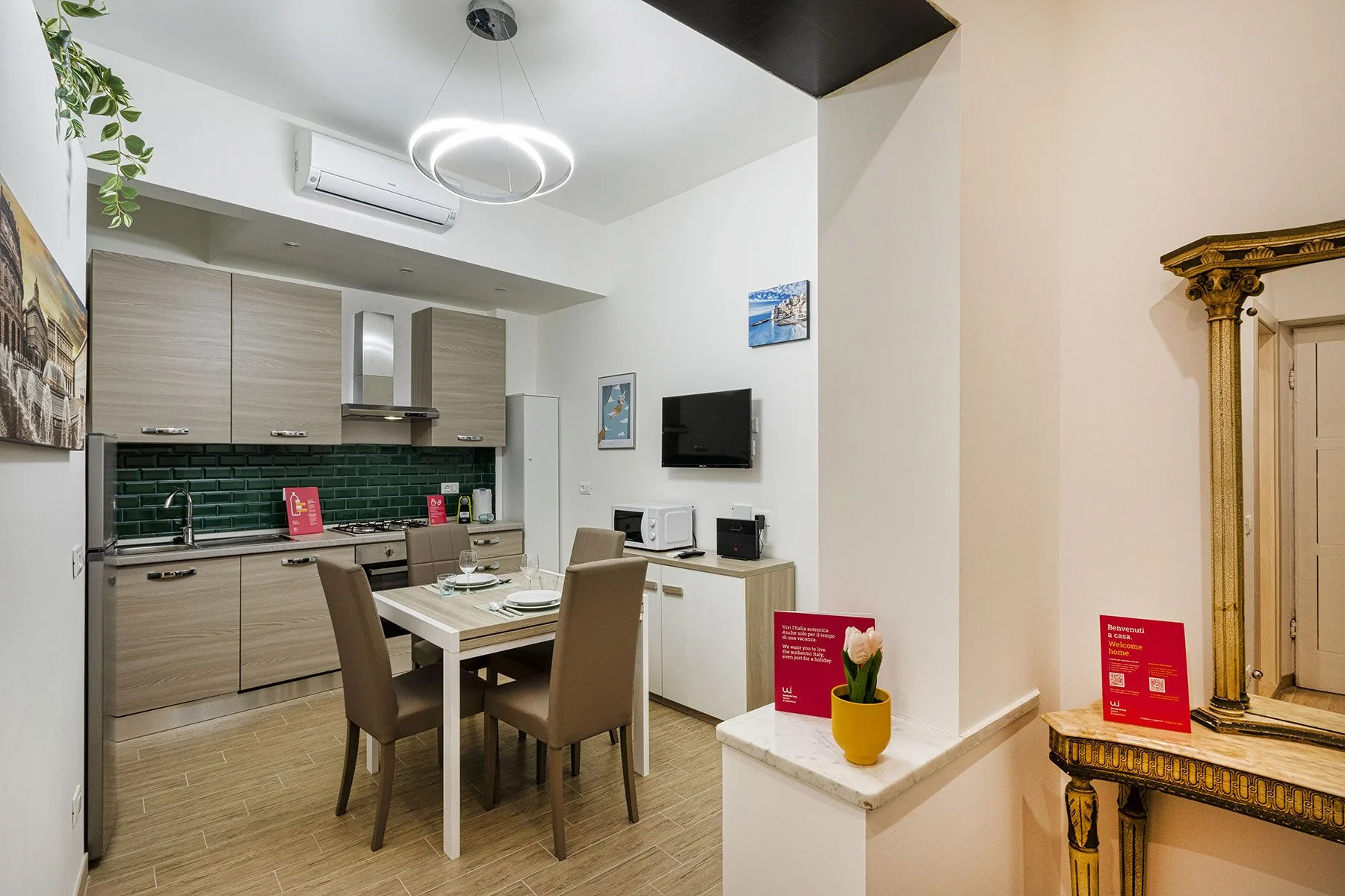 A dining area beside a compact kitchen, with a table and wall-mounted television.