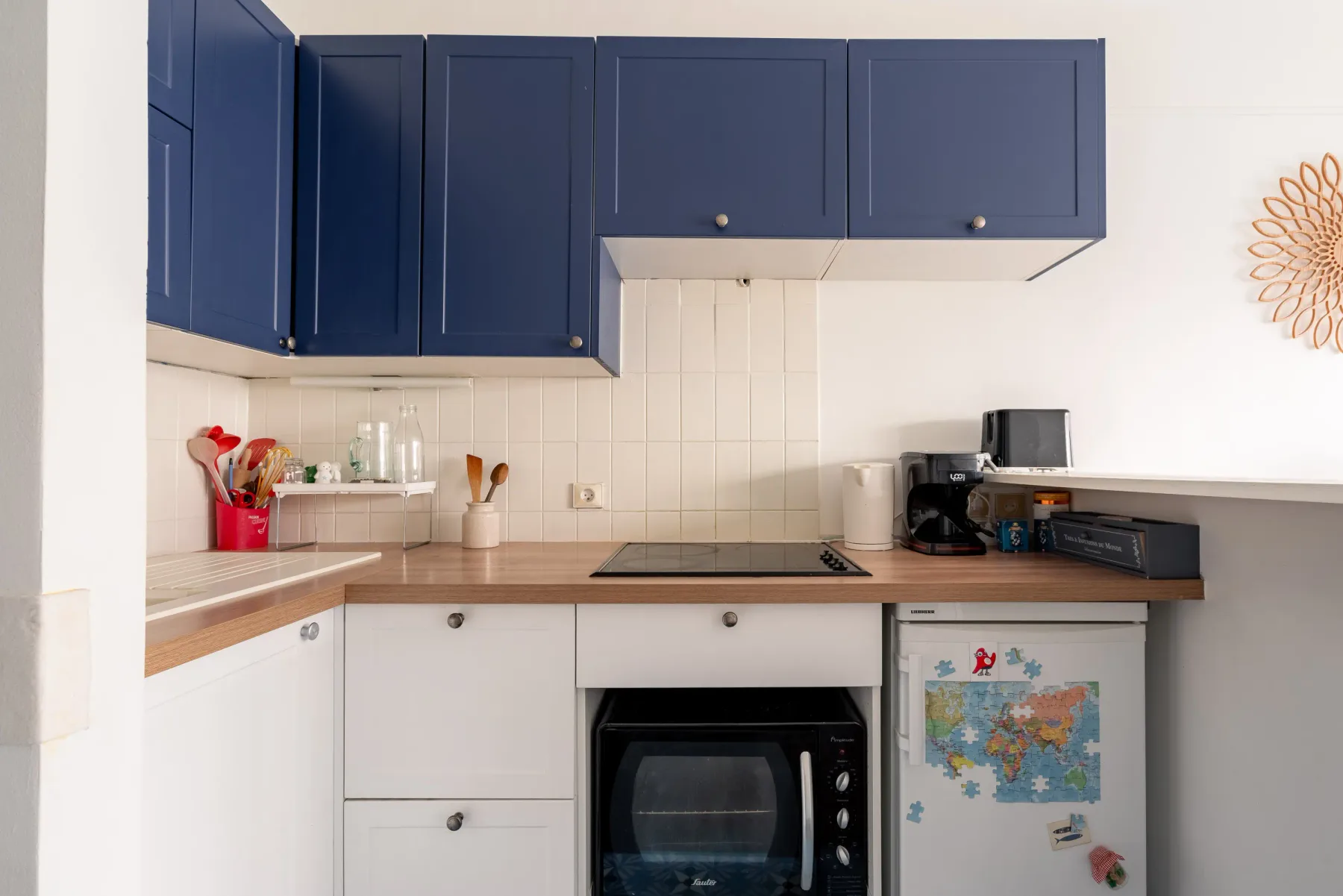 A compact kitchen with dark blue cabinets, a countertop, and small appliances.