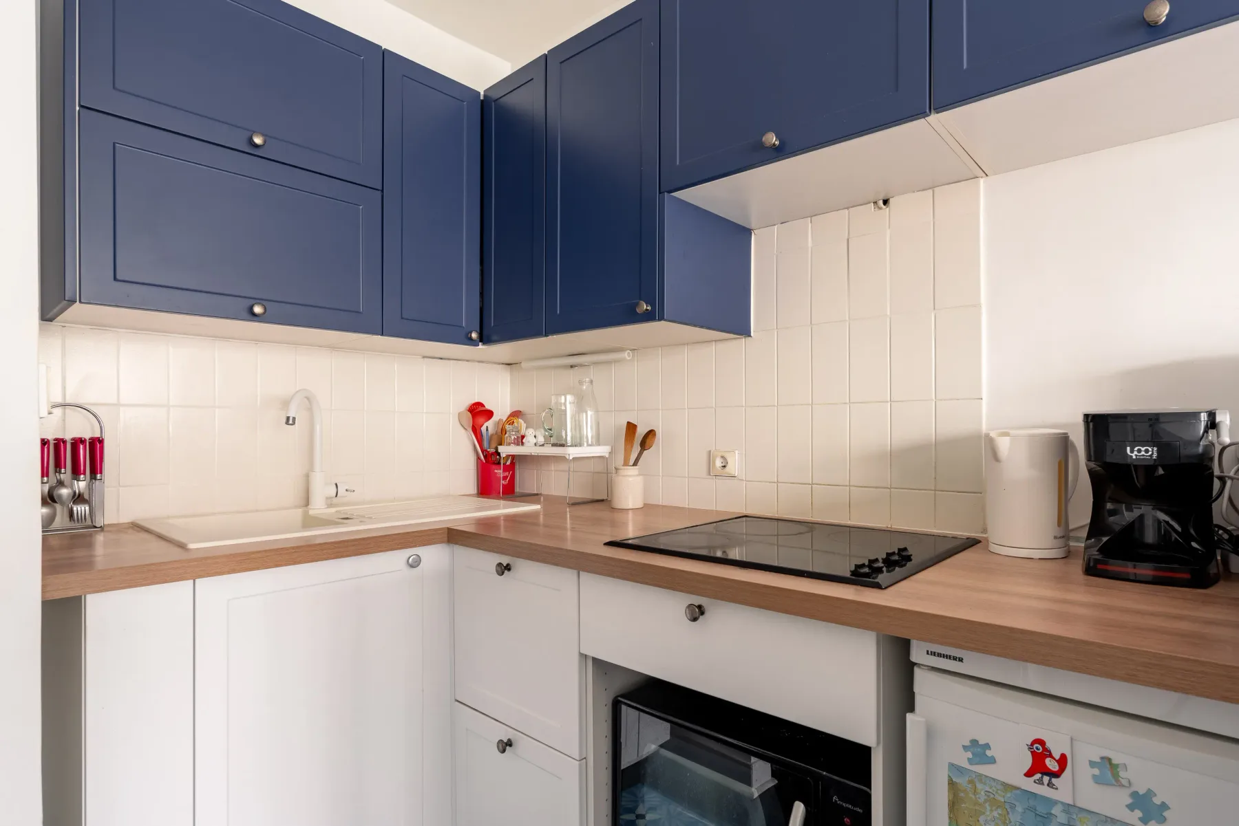 A kitchen with blue cabinets, light countertops, and a built-in cooktop.