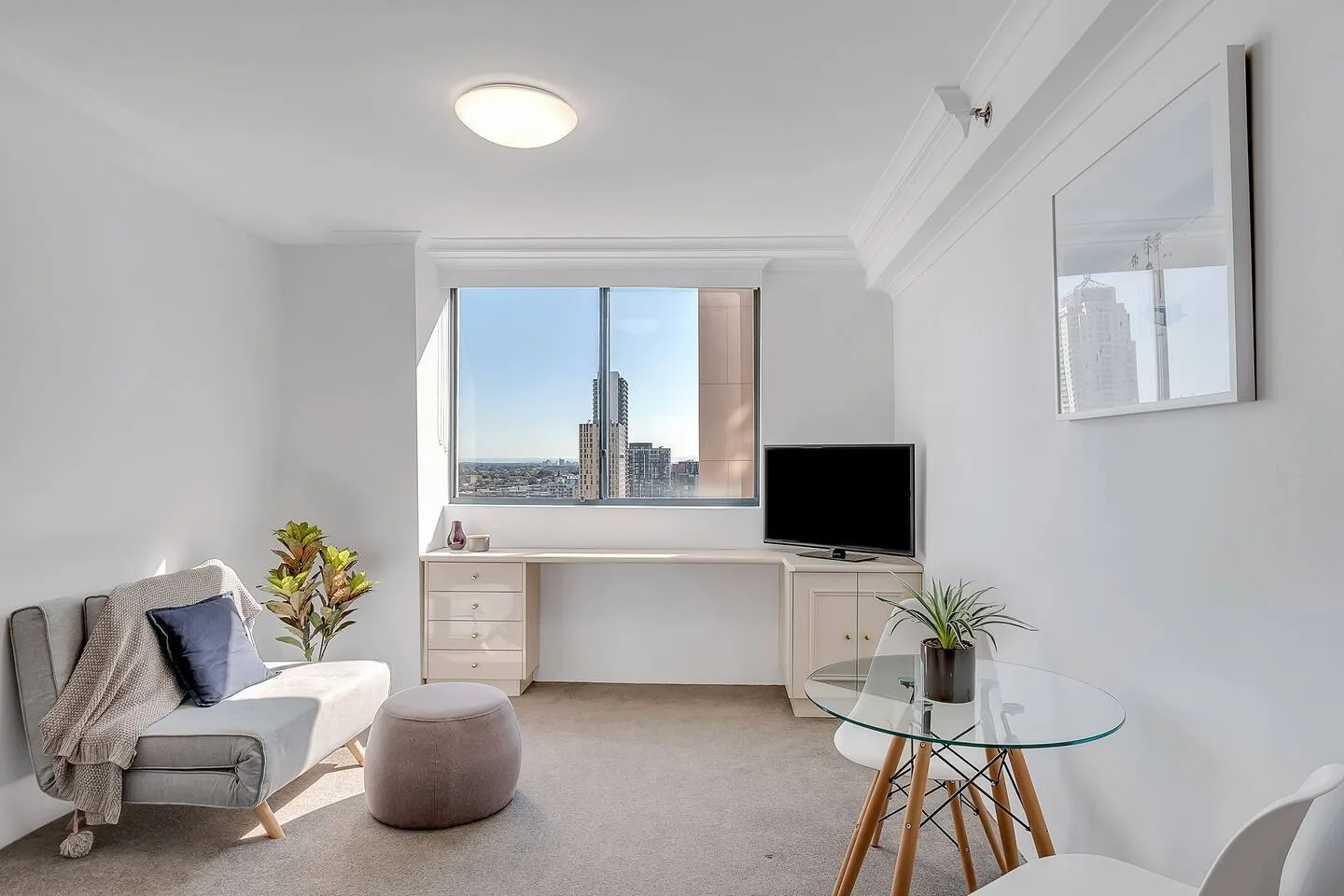Una sala de estar luminosa con una zona de descanso, escritorio y televisor.