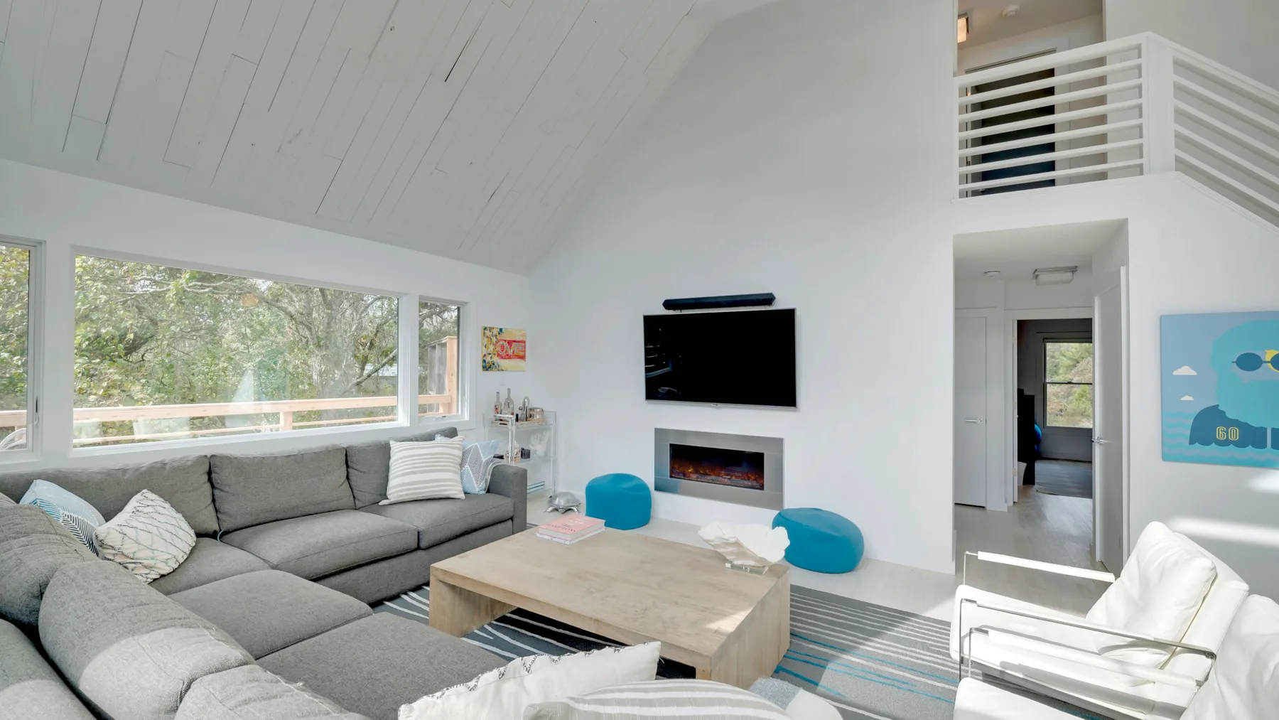 A bright living room with a sectional sofa, coffee table, and wall-mounted television.