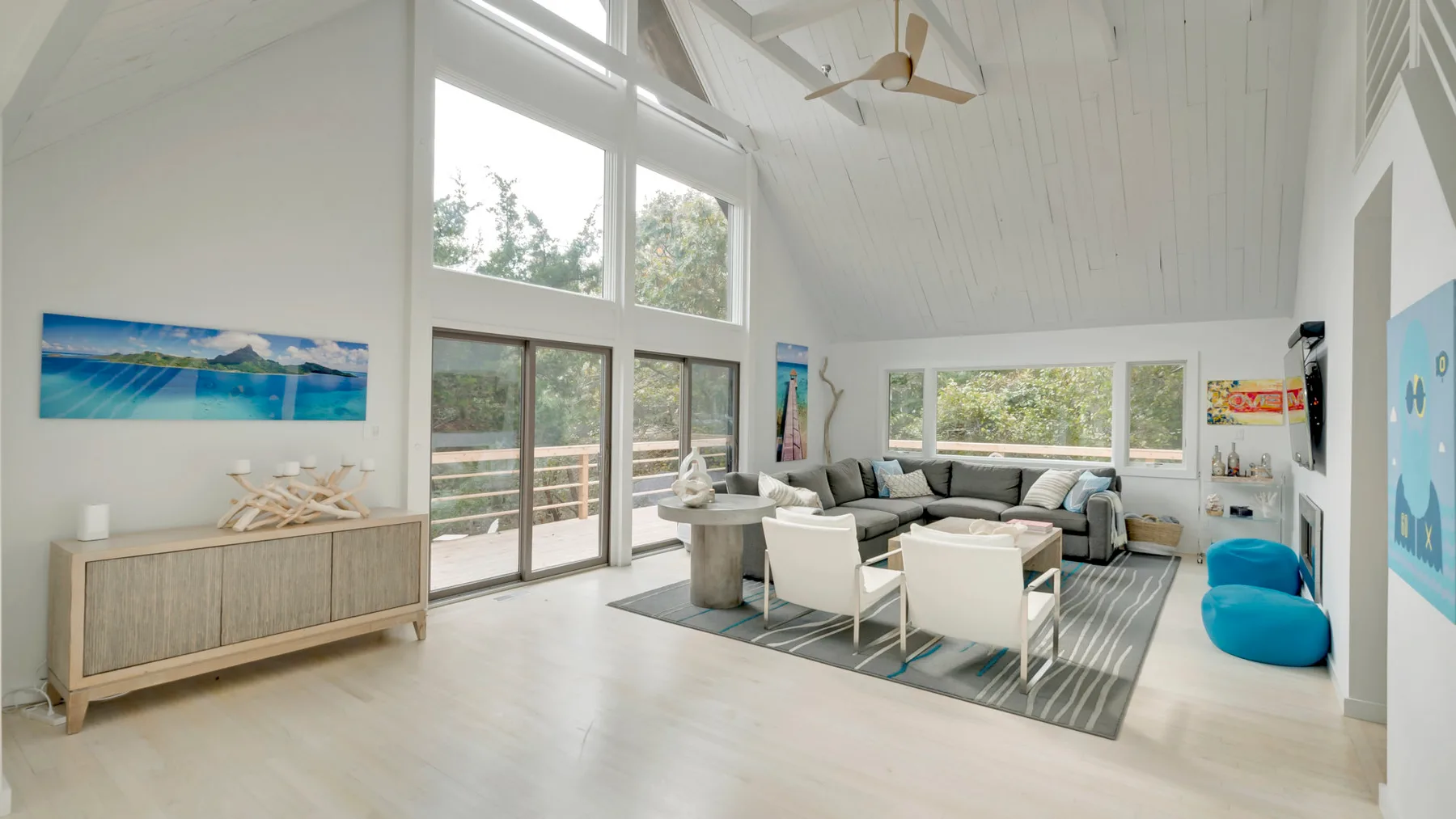 A bright living room with high windows, seating, and a dining table.