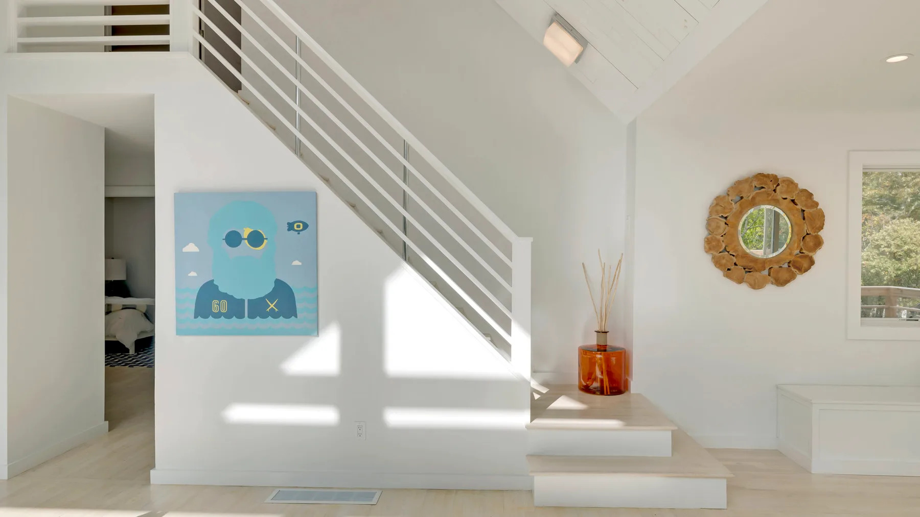 A bright interior foyer with a staircase, wall art, and a small console table.
